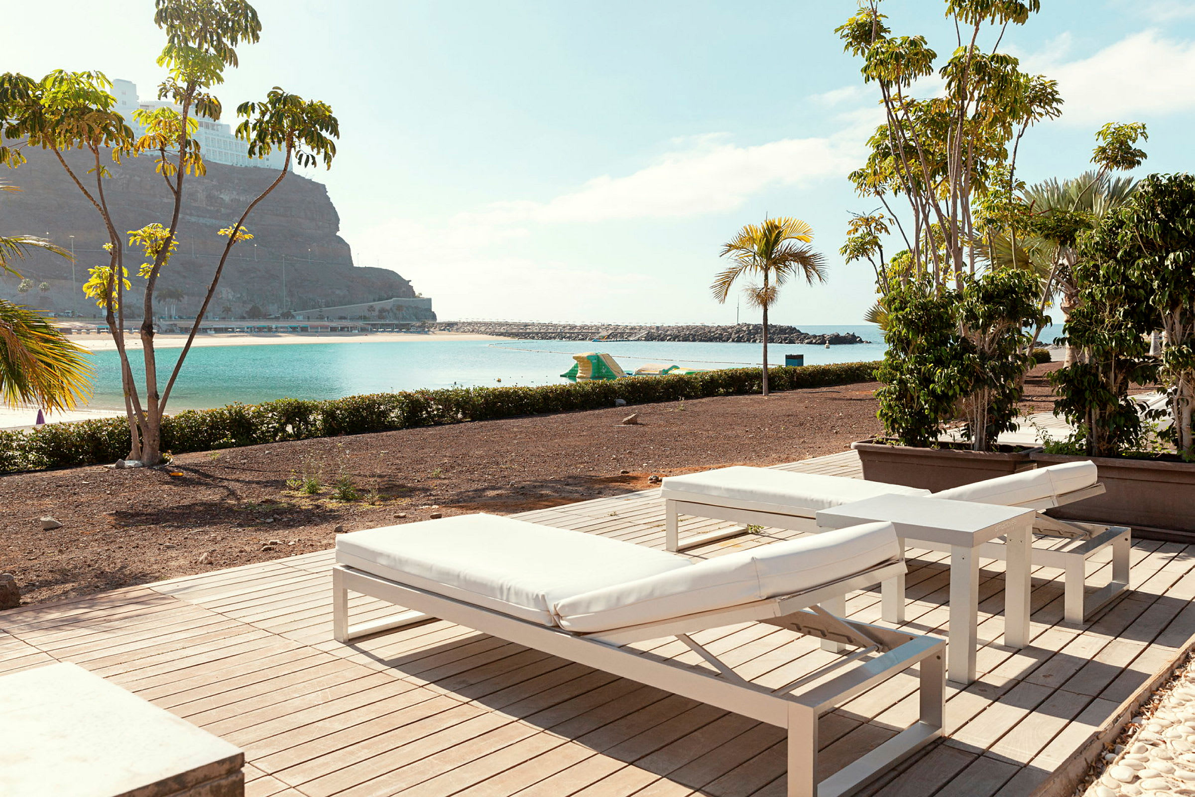Solstoler på en terrasse med utsikt over en strand og havet. (AI-generert tekst)