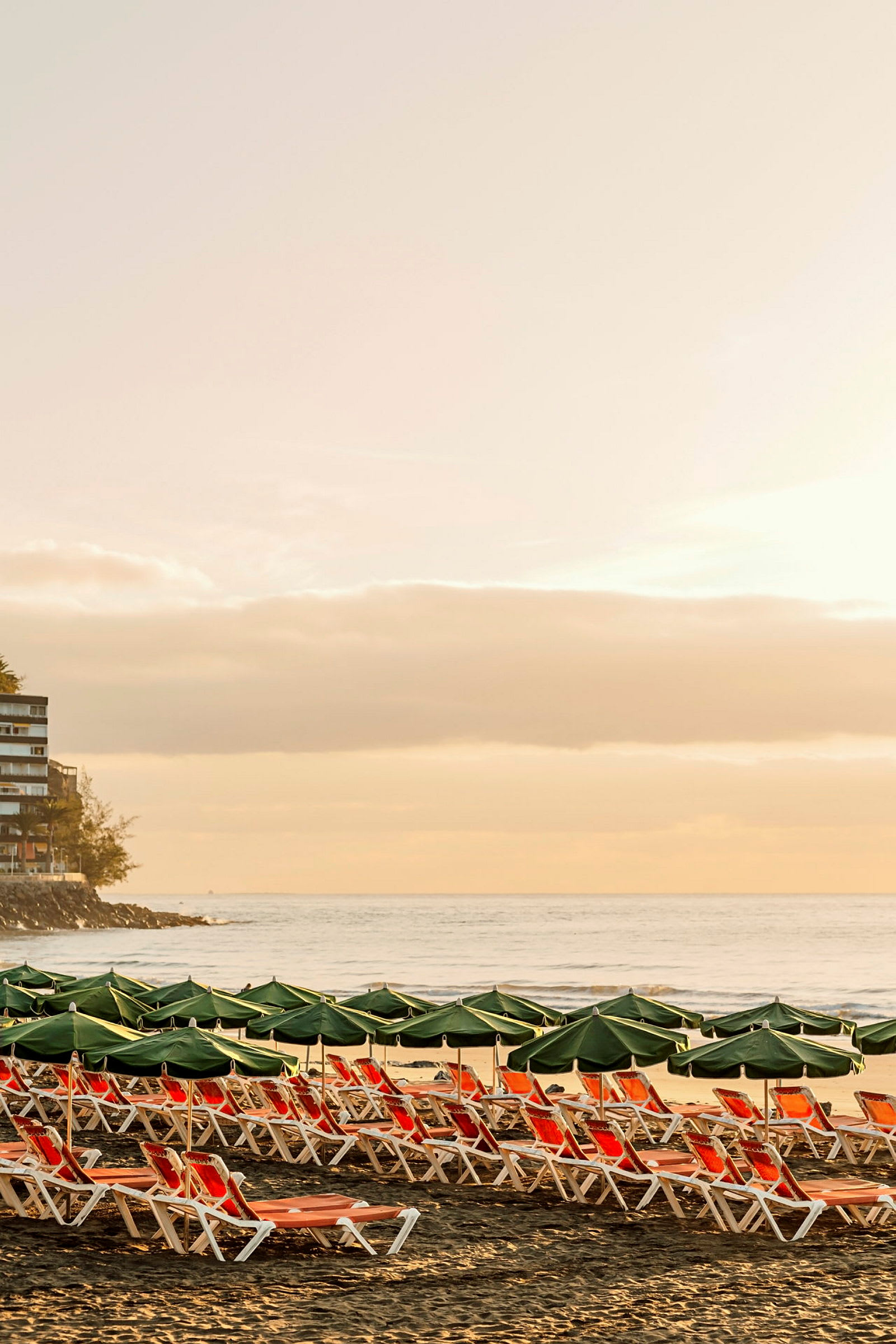 Solstoler og parasoller på en strand ved soloppgang eller solnedgang. (AI-generert tekst)