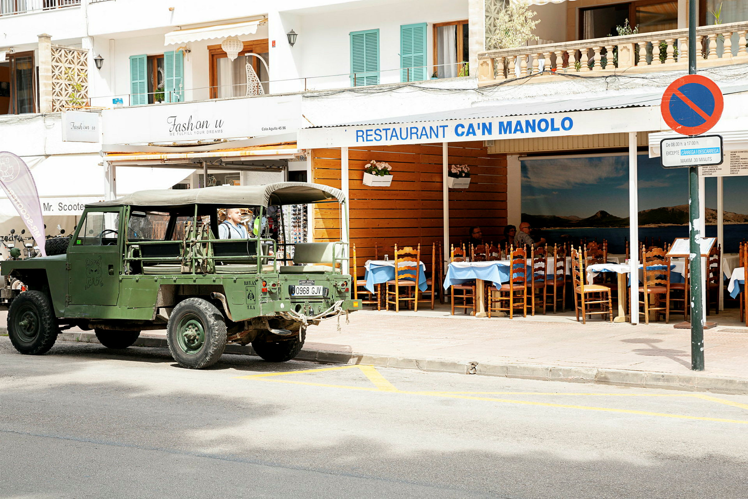 En grønn militærjeep parkert foran restauranten Can Manolo. (AI-generert tekst)