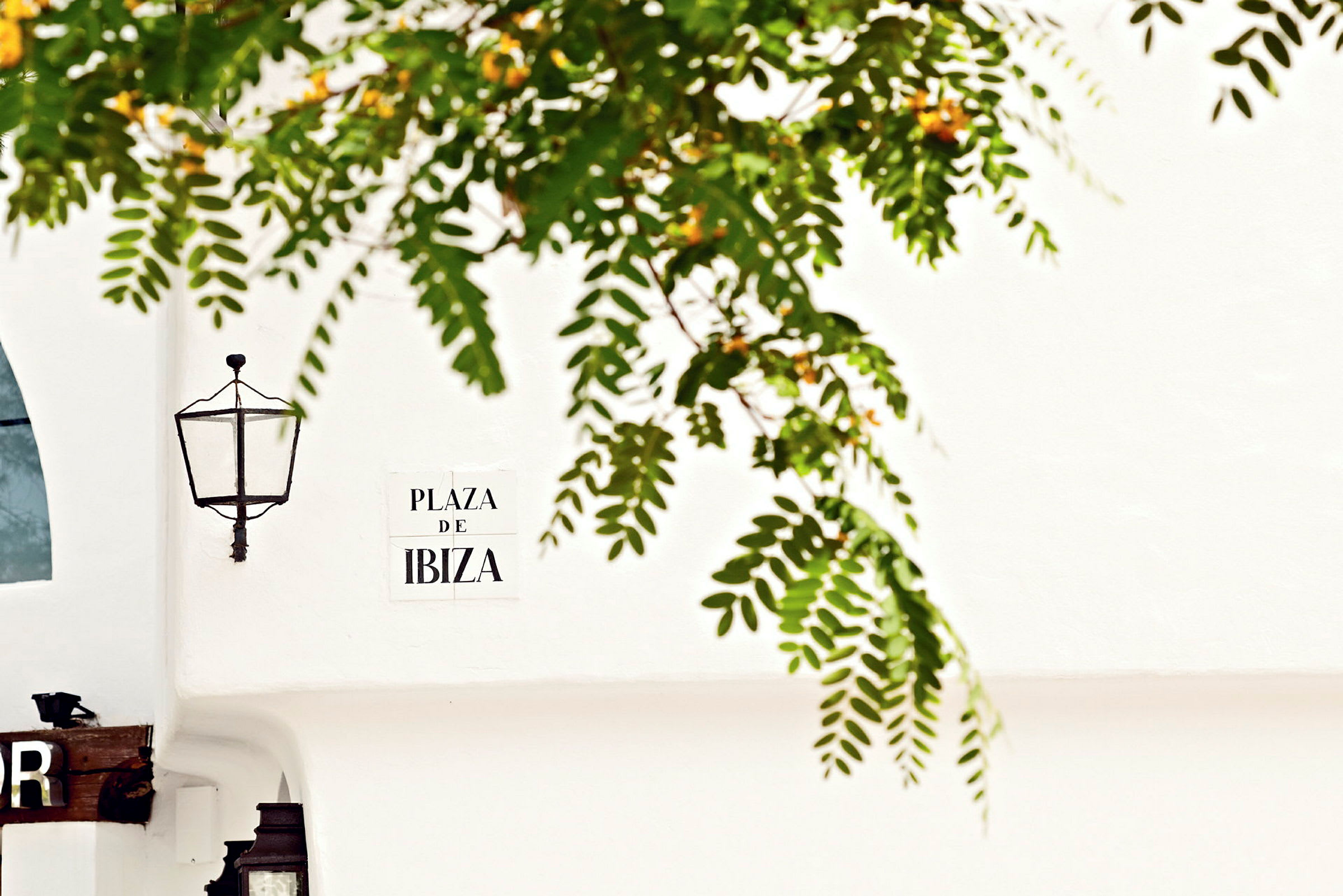 En vegg med en lampe og et skilt med teksten 'Plaza De Ibiza'. (AI-generert tekst)