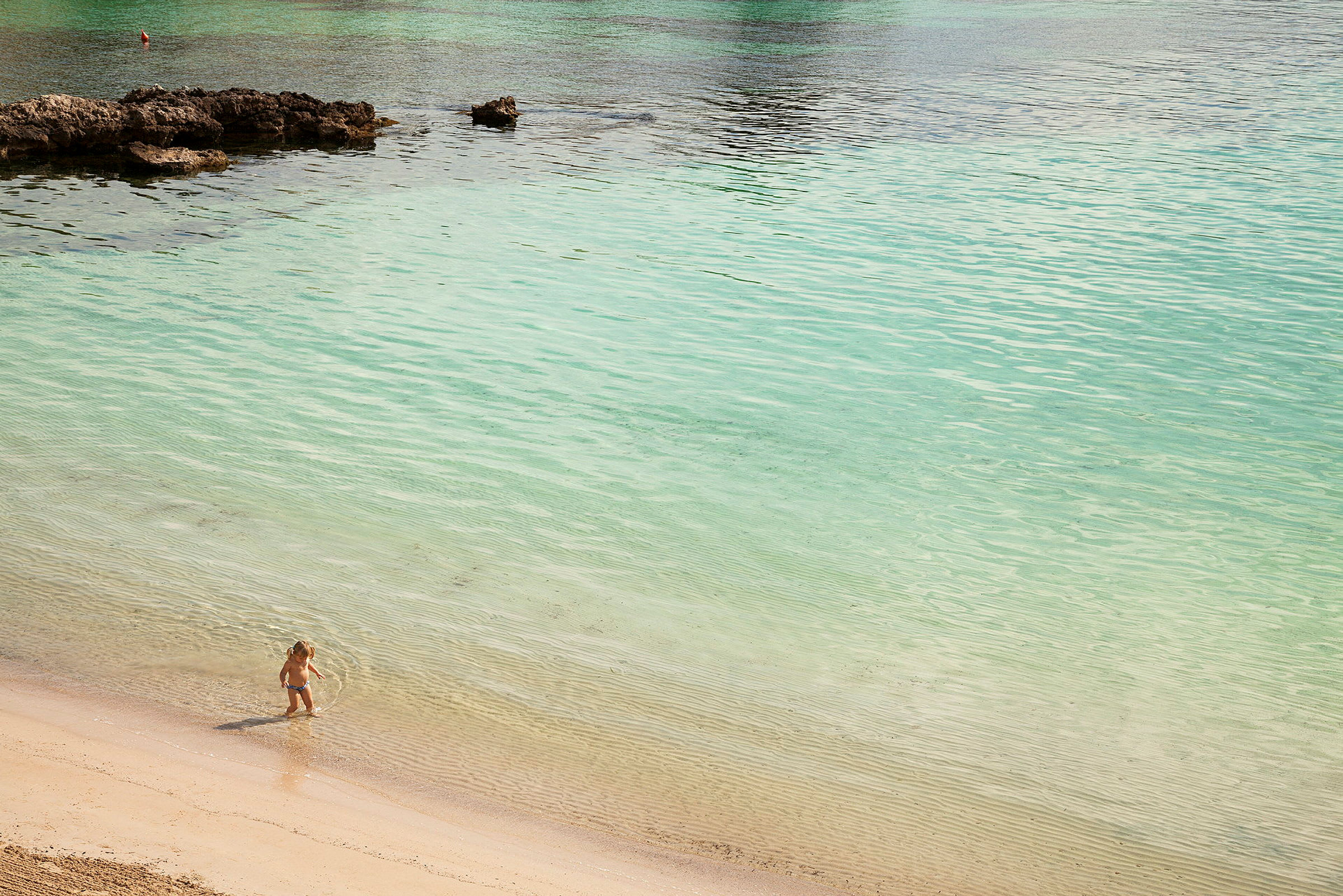 Et barn leker ved vannkanten på en strand. (AI-generert tekst)