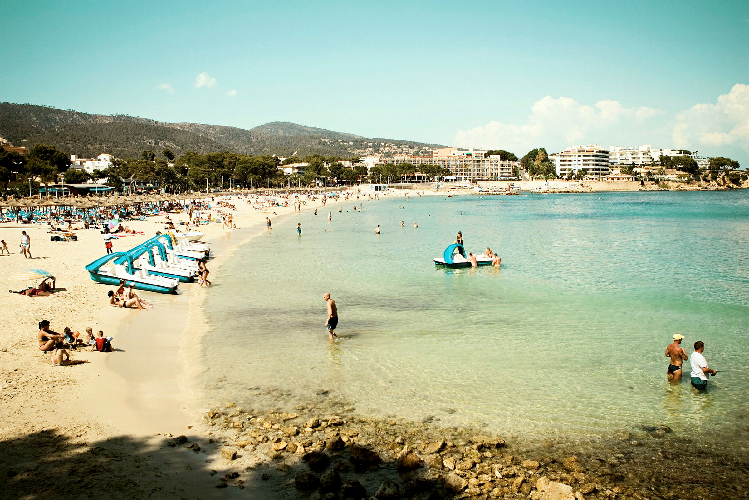 Strand med turkist vann og feriegjester. (AI-generert tekst)
