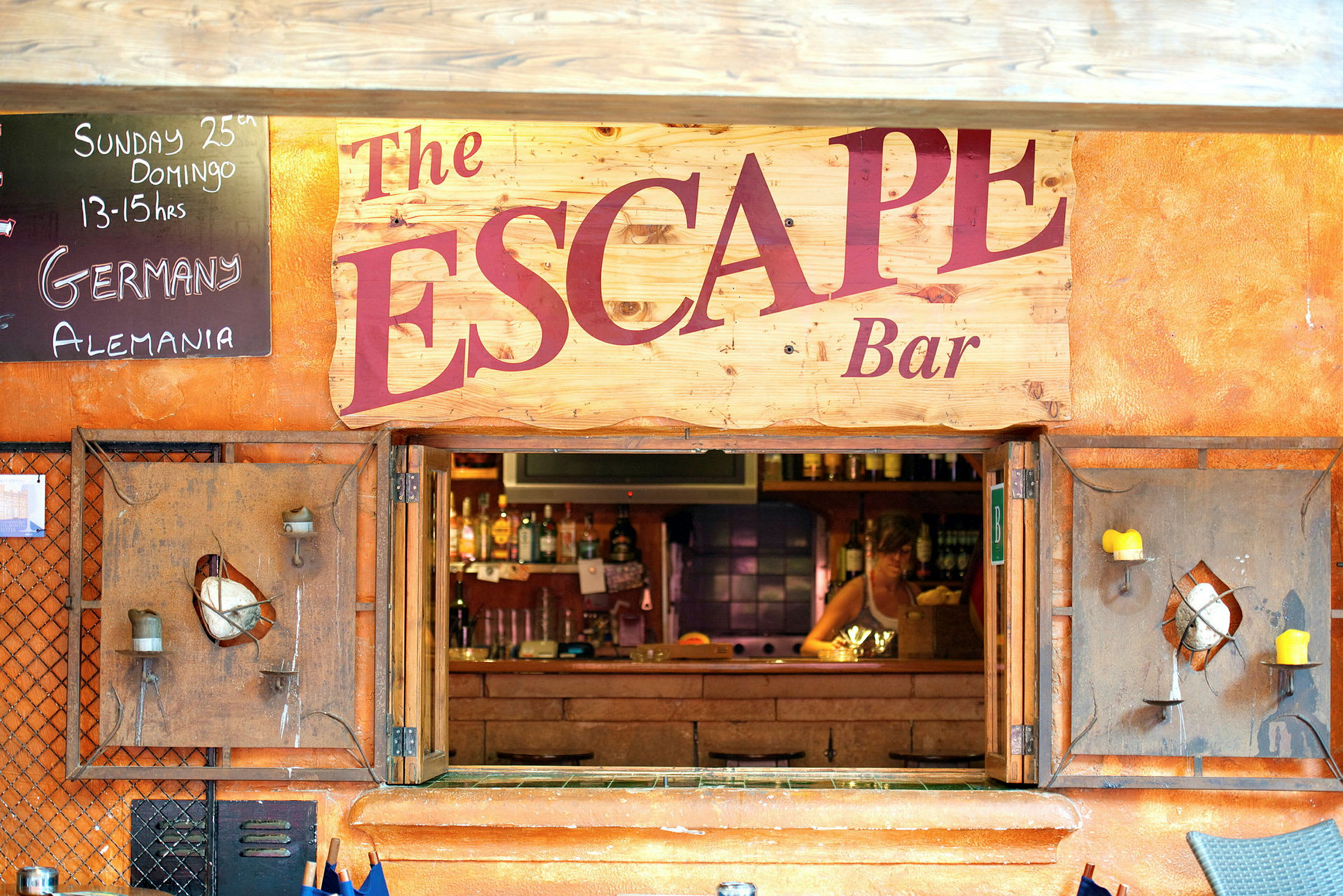 En bar med navnet 'The Escape' vises, inkludert et skilt med tekst og en åpning til baren. (AI-generert tekst)