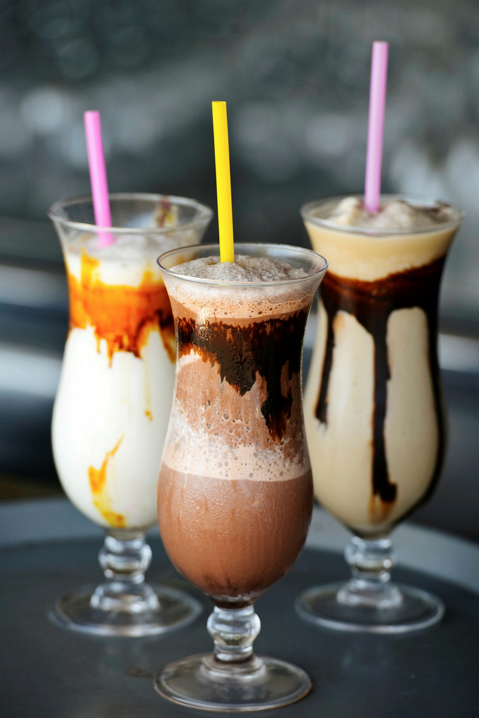 Tre iskremshakes med ulike smaker, toppet med sugerør. (AI-generert tekst)