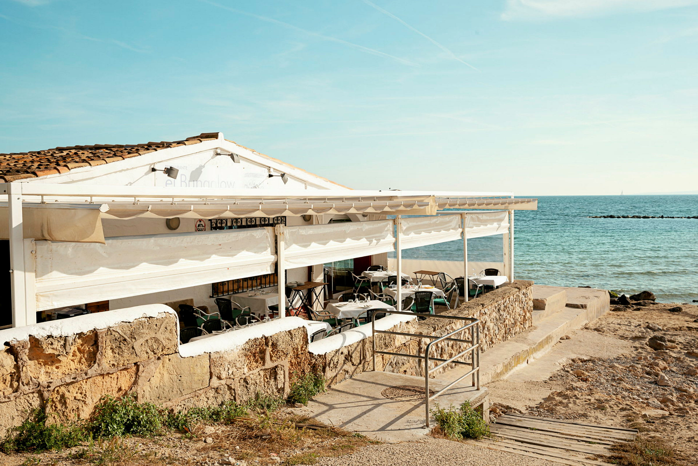 En restaurant med uteservering ved havet. (AI-generert tekst)