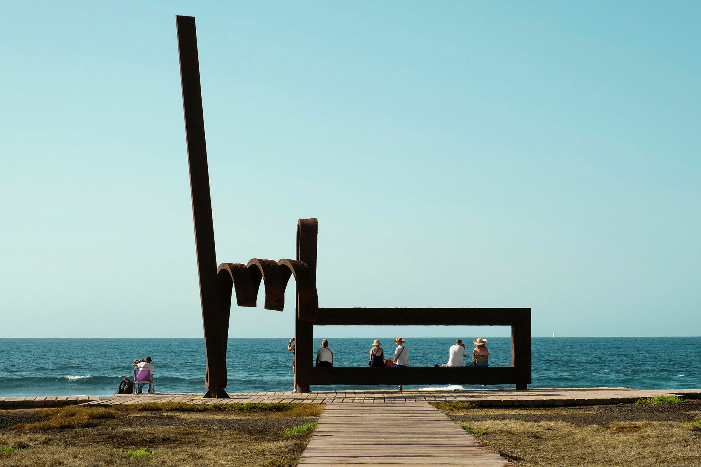 Skulptur med mennesker som sitter ved havet. (AI-generert tekst)