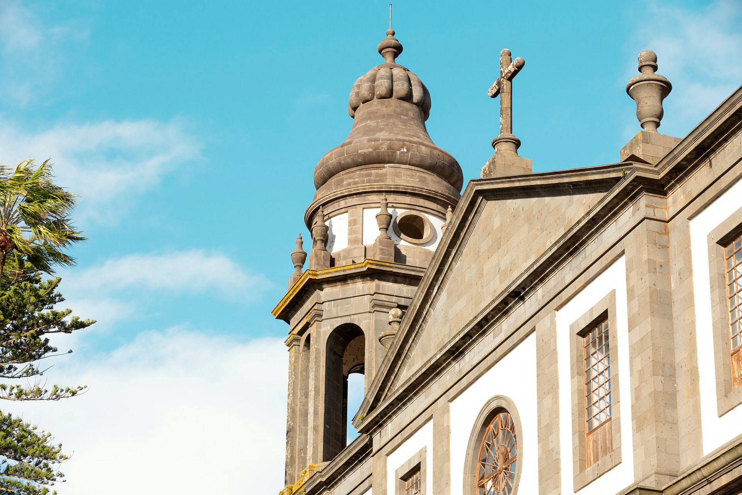 Nærbilde av en kirke med detaljer på kuppel og kors mot klar blå himmel. (AI-generert tekst)