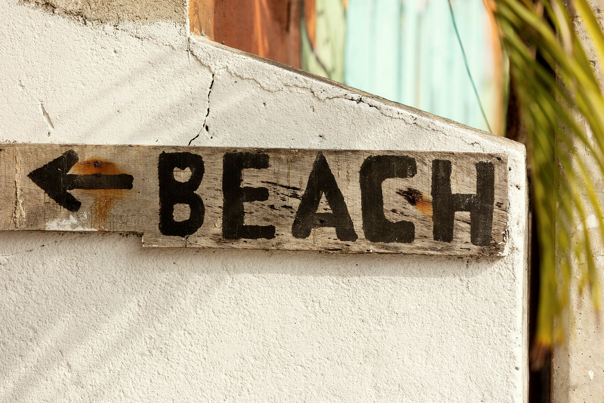 Et treskilt med teksten "BEACH" og en pil peker til venstre. (AI-generert tekst)