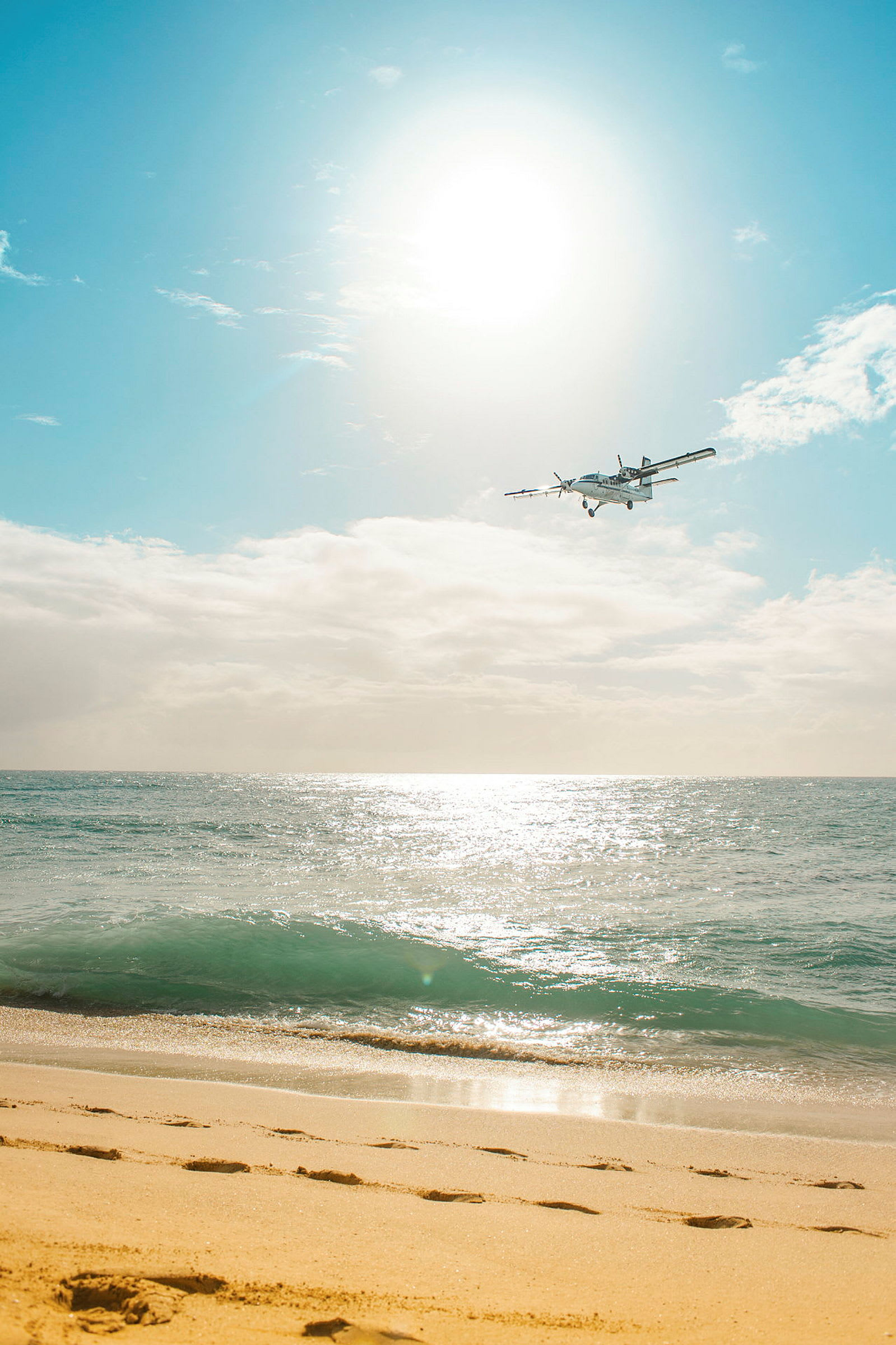 Et fly flyr over en strand og hav under en lys himmel. (AI-generert tekst)