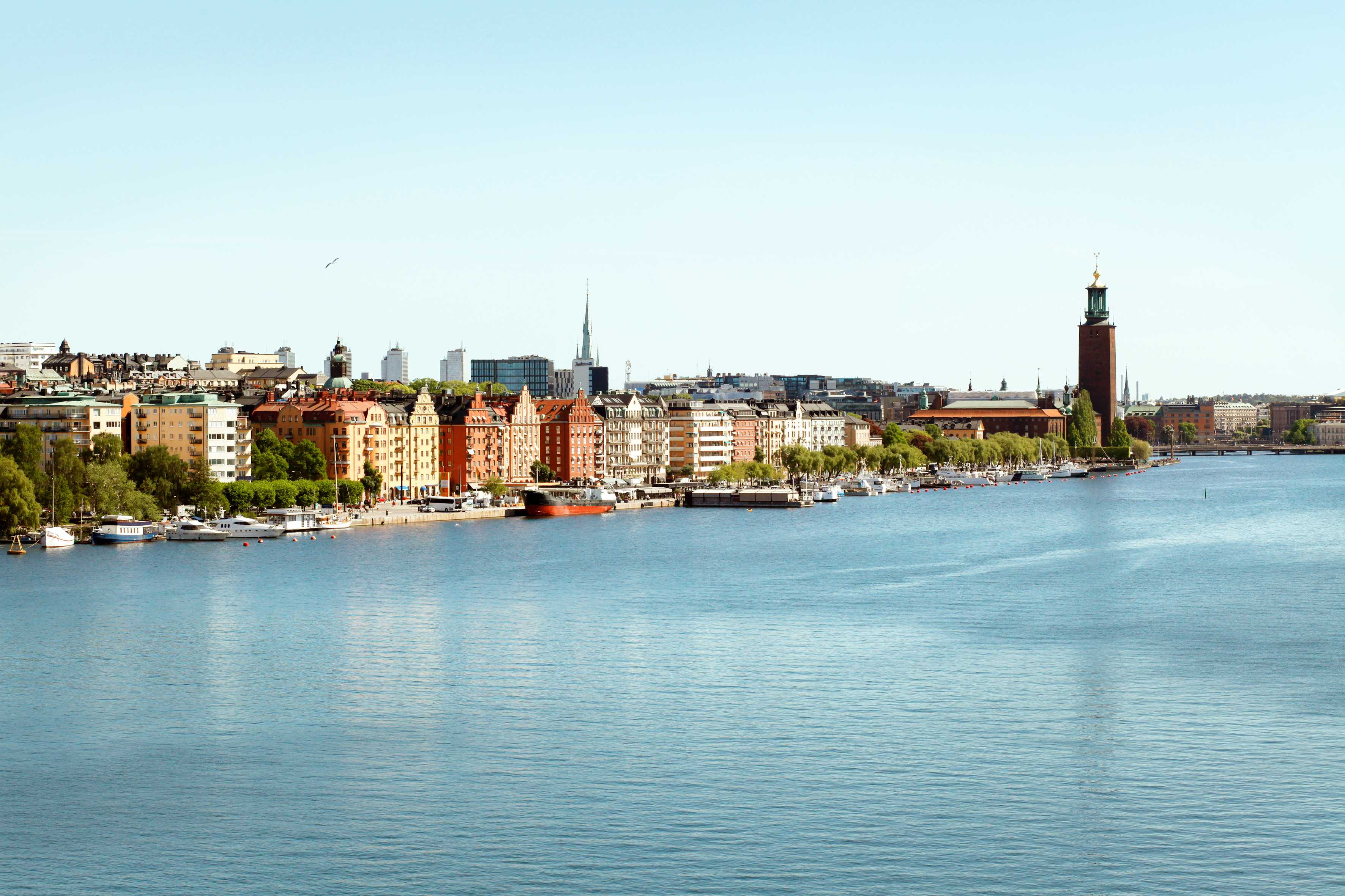 Bymiljø ved et vannspeil med bygninger og båter i forgrunnen. (AI-generert tekst)