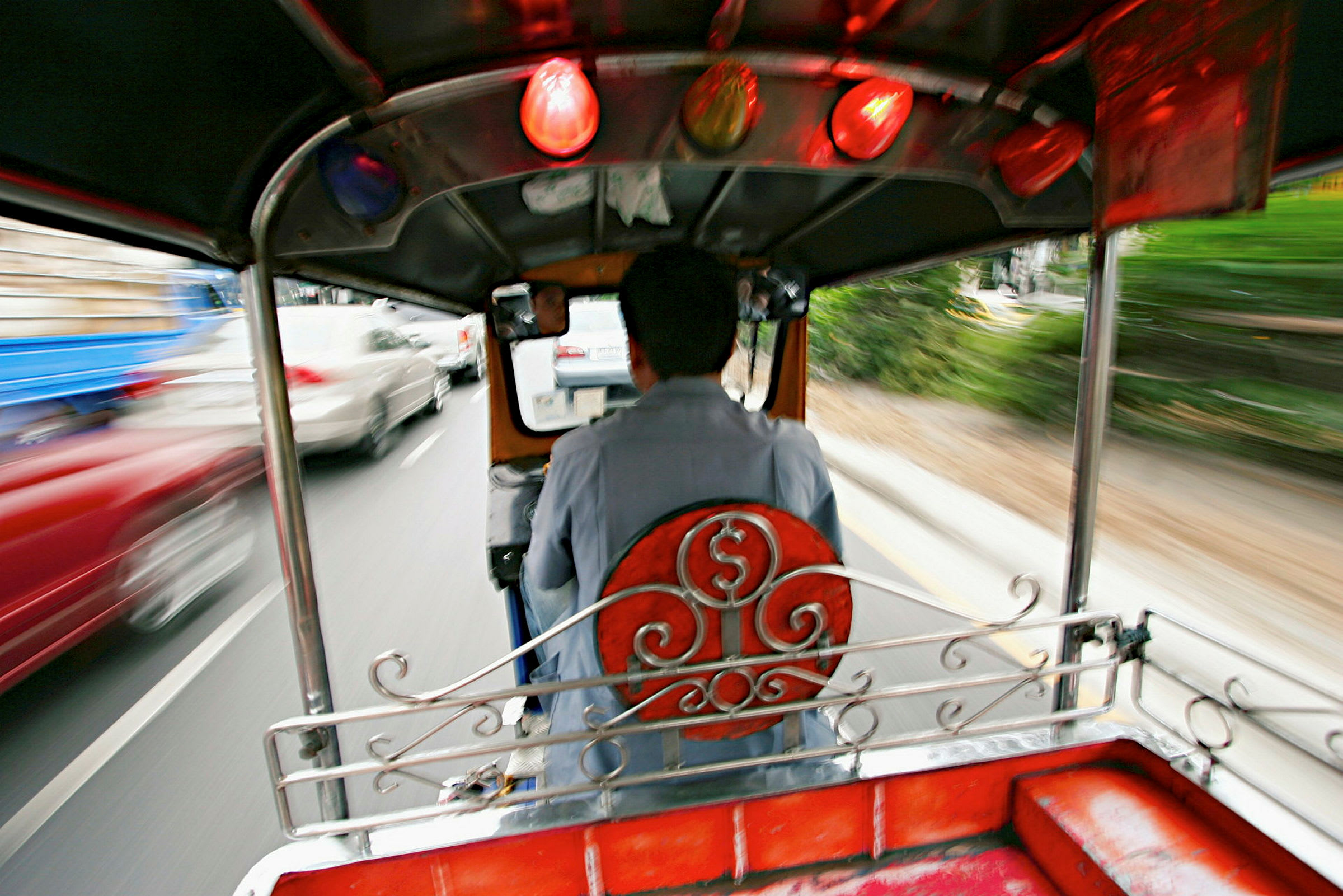 En sjåfør kjører en tuk-tuk på en trafikkert vei. (AI-generert tekst)