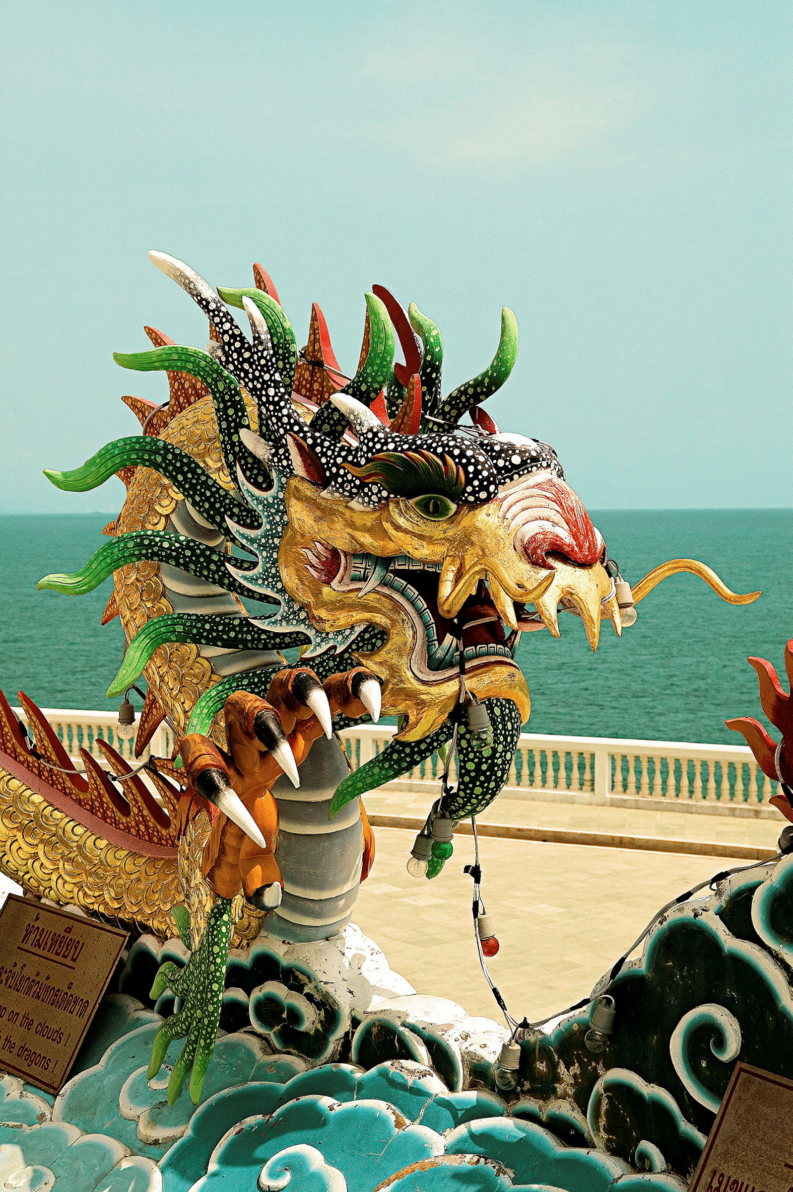 Fargerik drage-statue ved en strandpromenade. (AI-generert tekst)