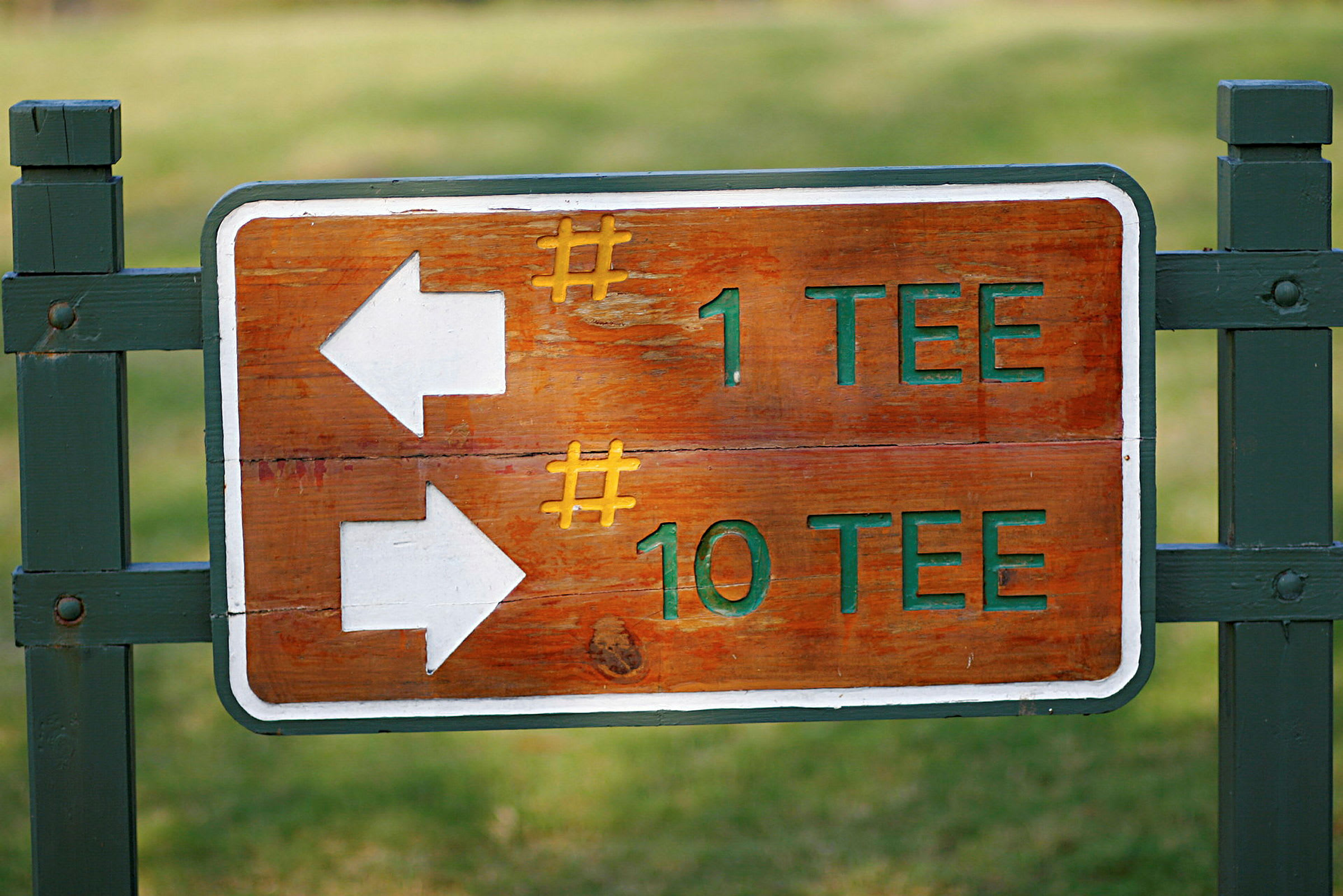 Treskilt med tekst som viser retning med piler til golfbanens første og tiende startpunkt. (AI-generert tekst)
