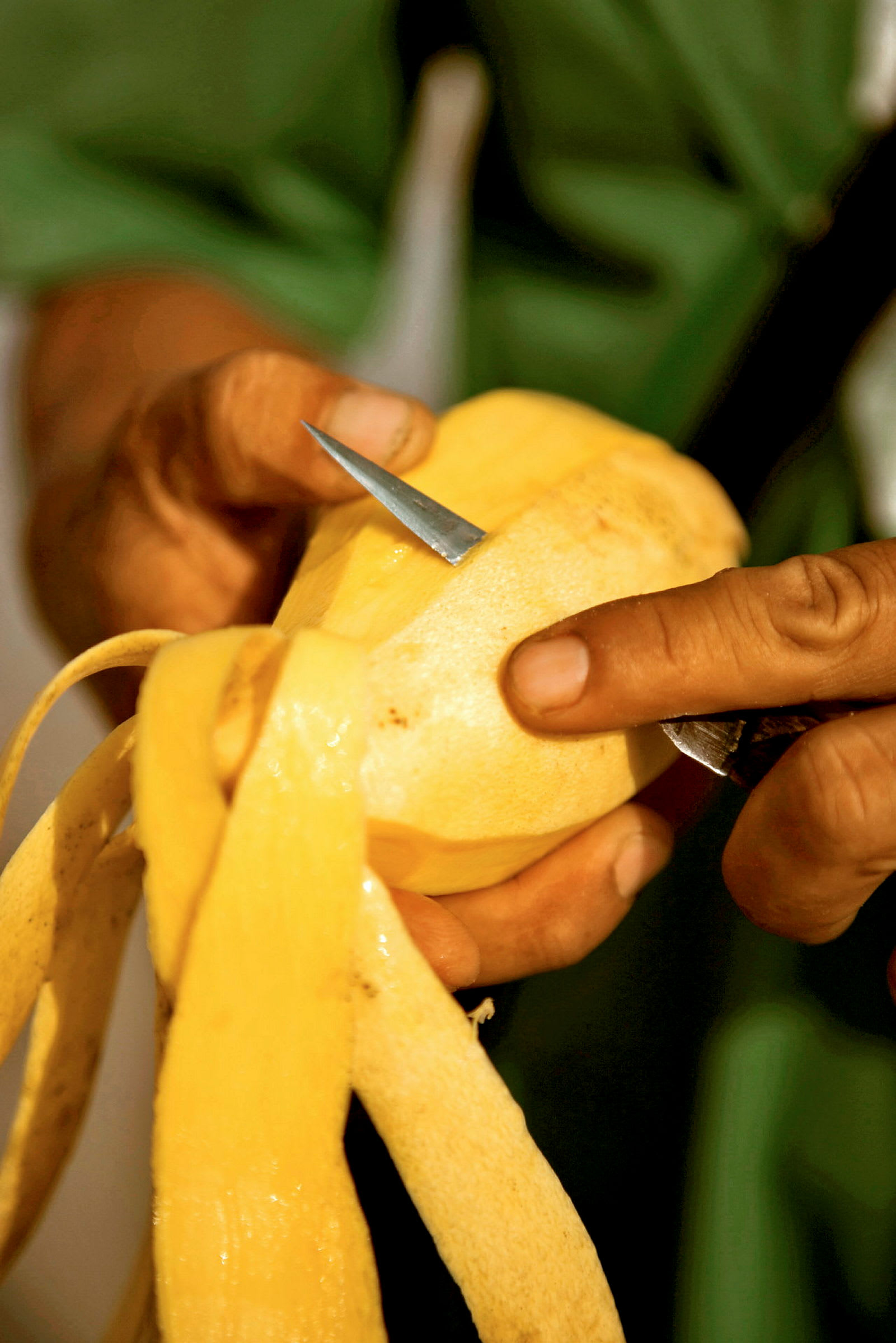 En hånd skreller en mango med en liten kniv. (AI-generert tekst)