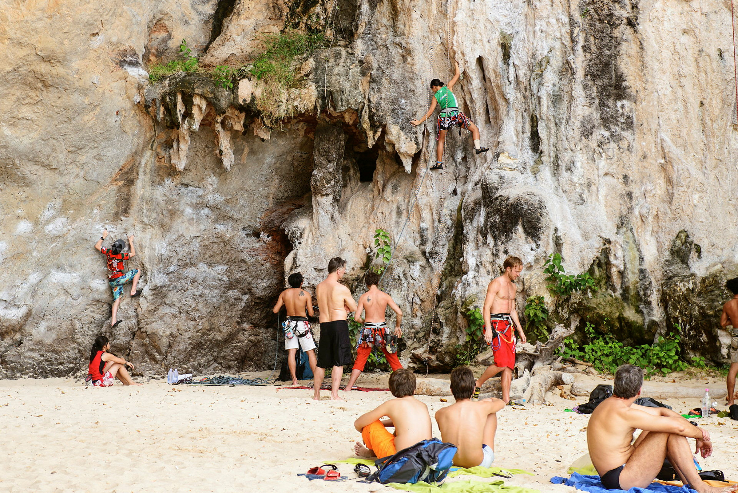Personer klatrer på klipper nær en strand. (AI-generert tekst)