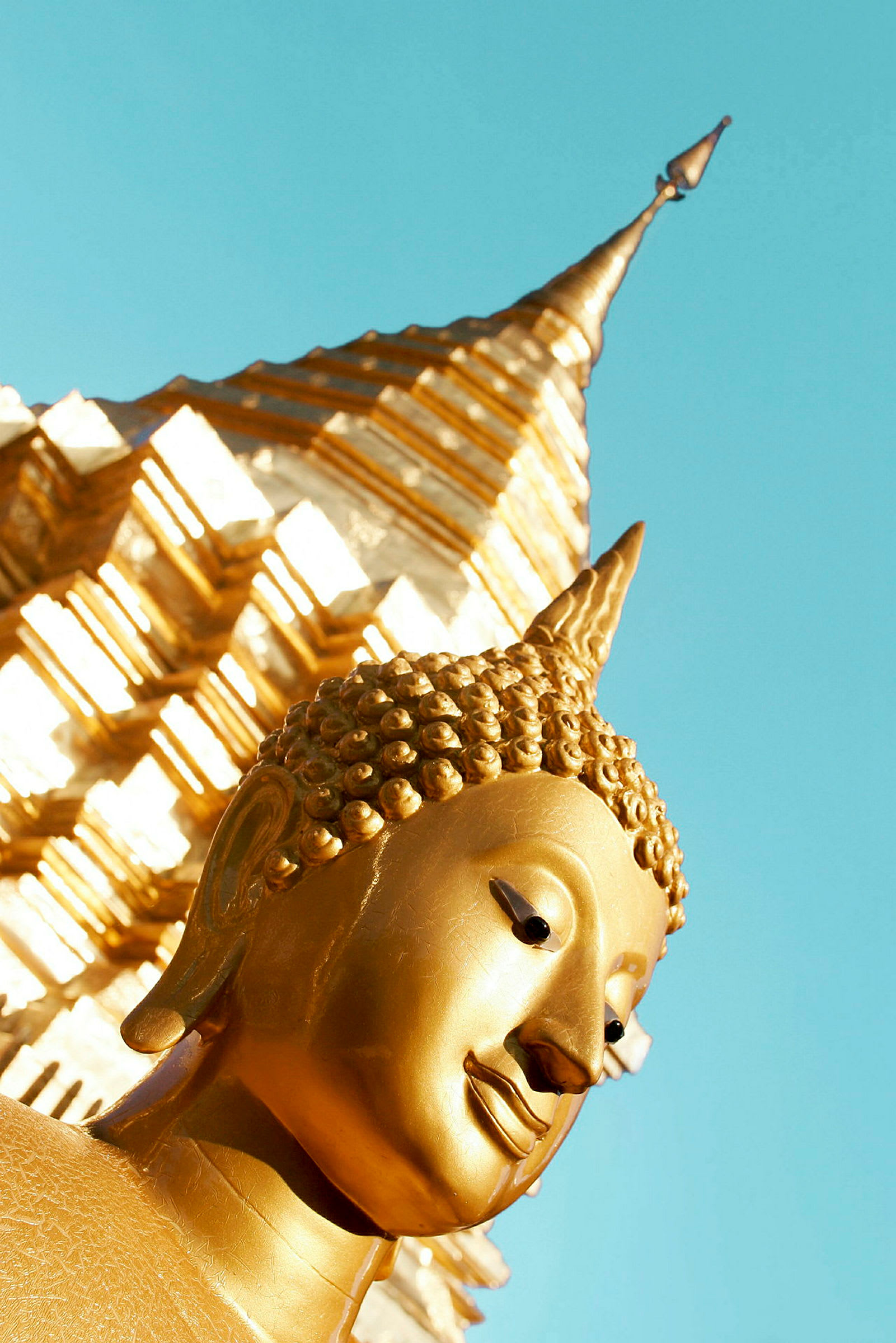 Gylne detaljer av en buddhistisk statue med en stupa i bakgrunnen. (AI-generert tekst)