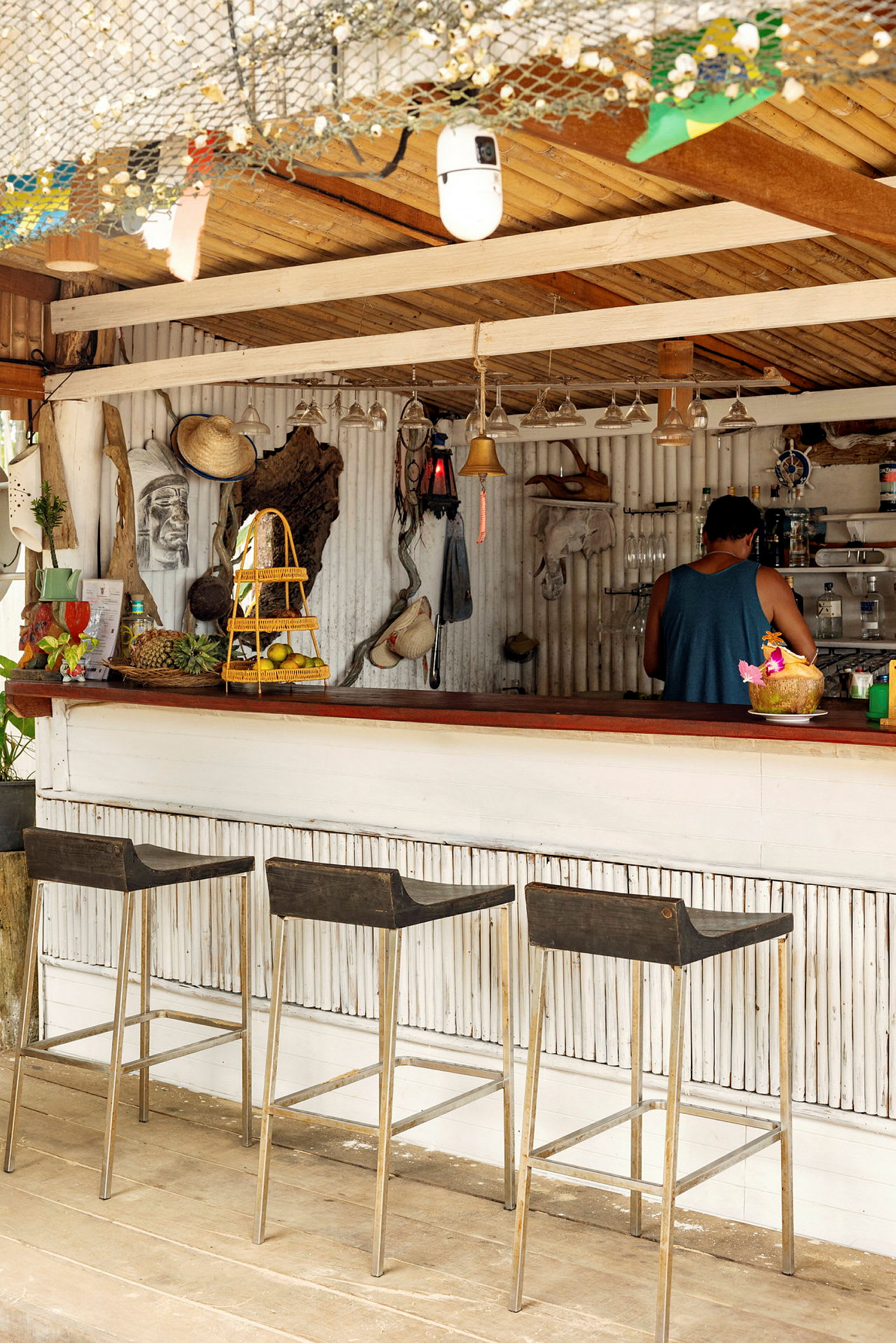 Bilde av en strandbar med tre krakker, dekorasjoner på veggen og en person ved disken. (AI-generert tekst)