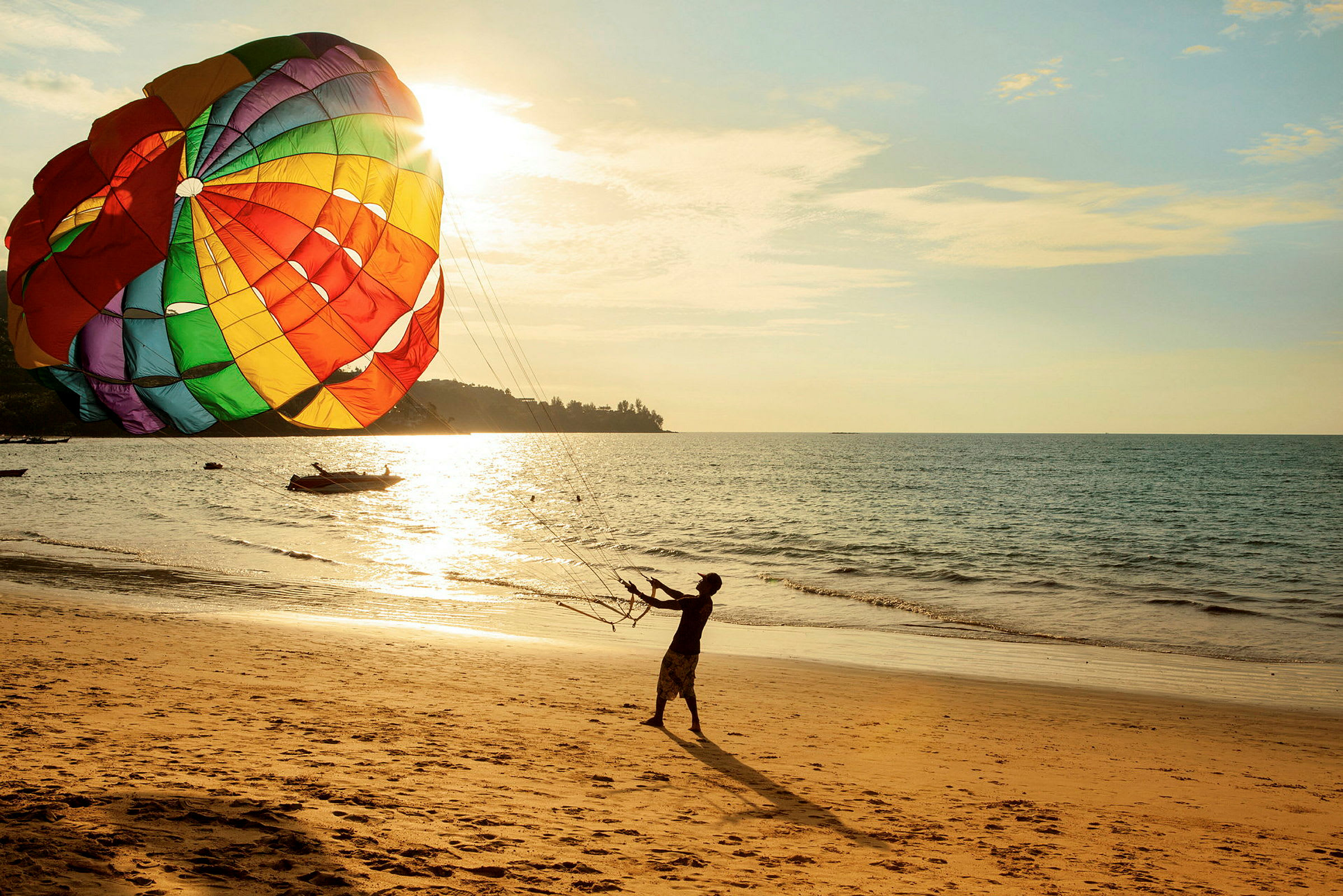 Person holder i liner til en stor fargerik parasail på en solfylt strand. (AI-generert tekst)