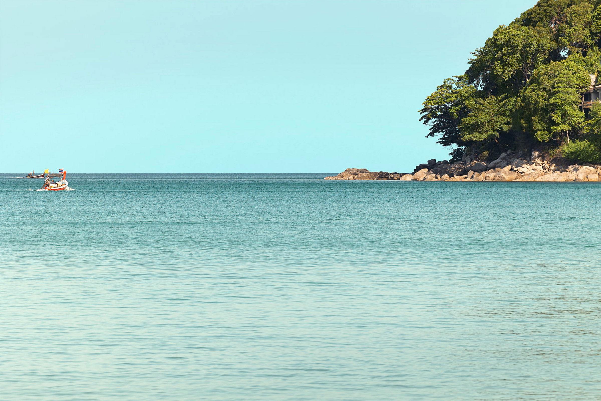 En båt på havet med en skogkledd odde i bakgrunnen. (AI-generert tekst)