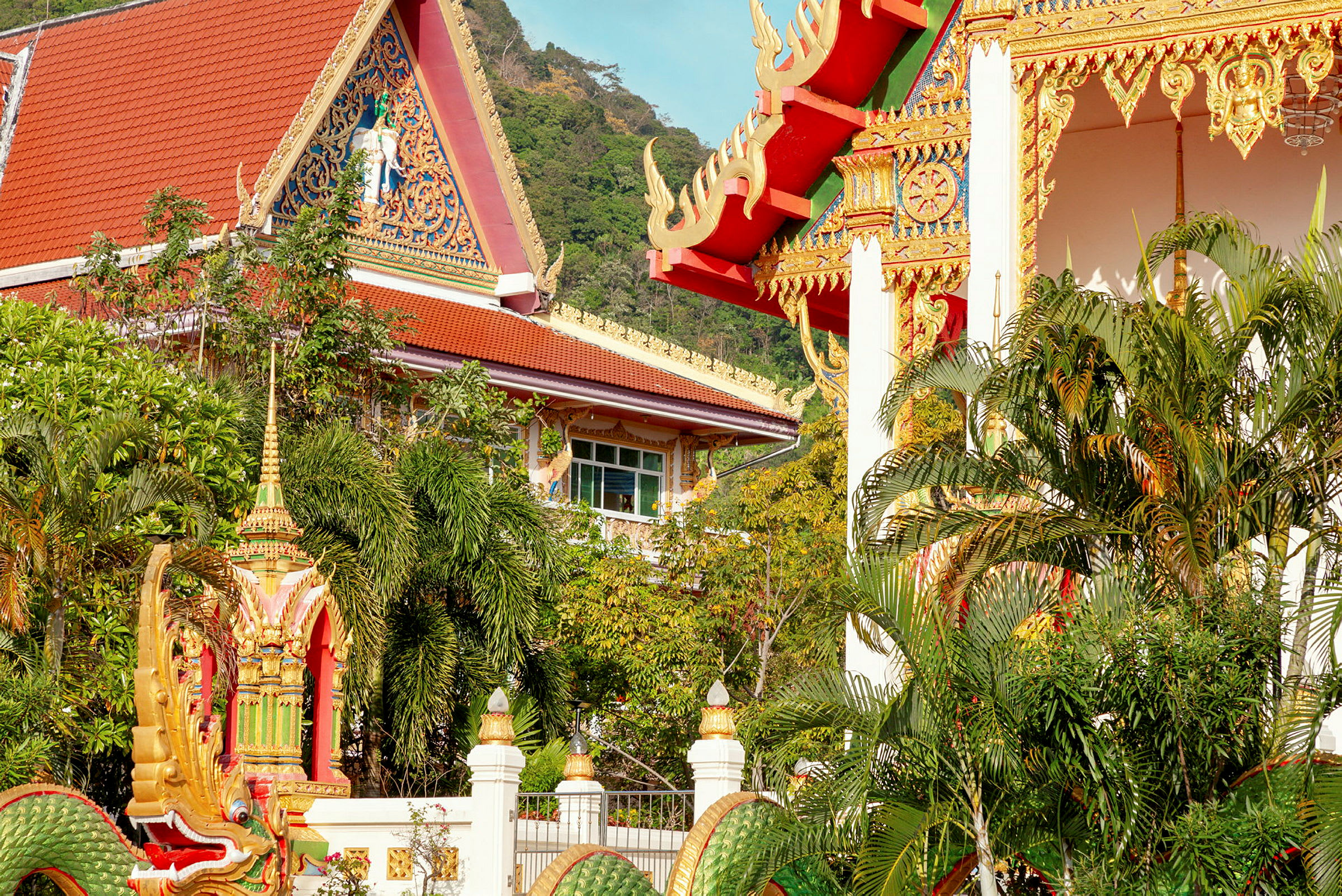 Bilde av en tradisjonell thailandsk bygning med dekorative detaljer omgitt av grøntområder. (AI-generert tekst)