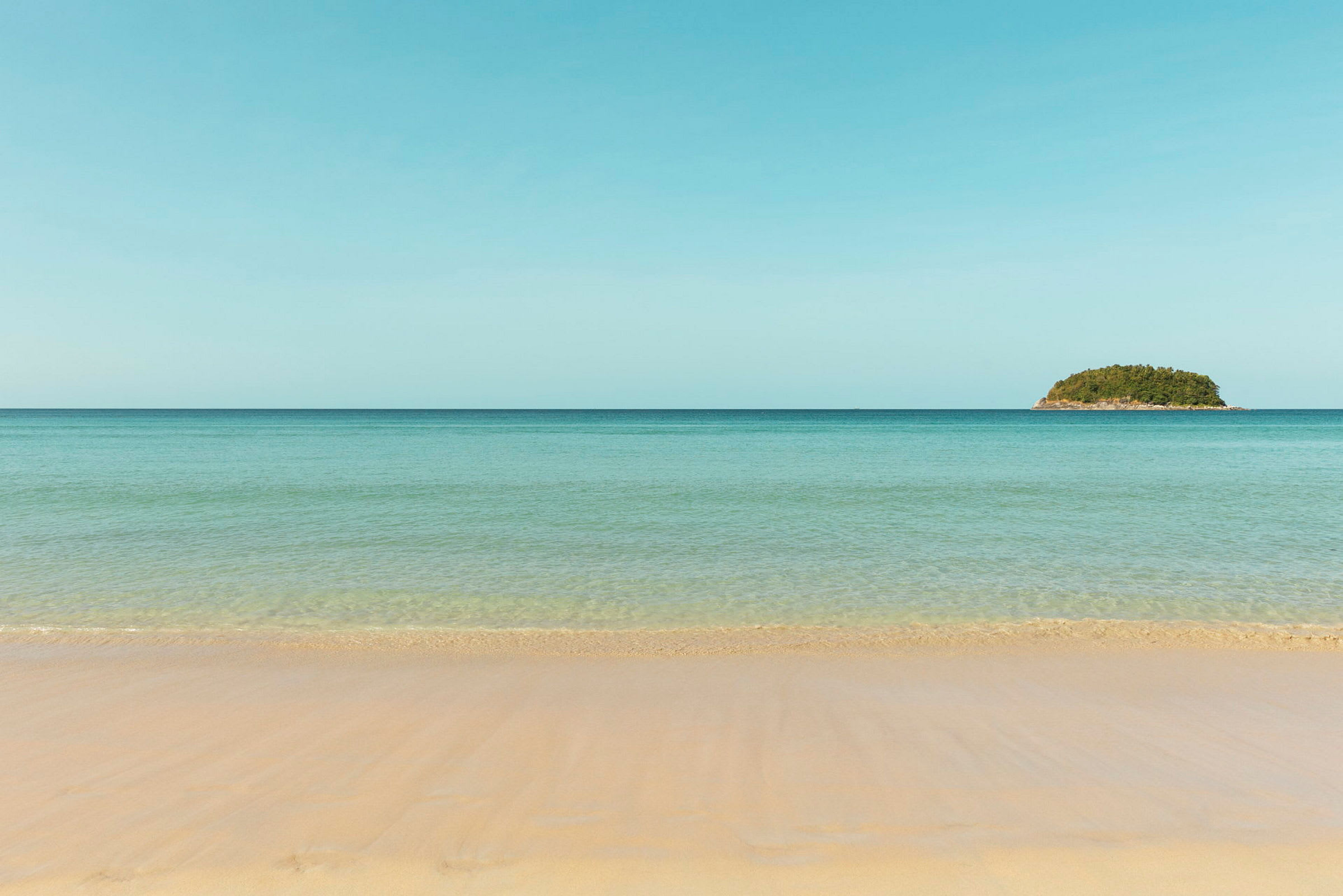 Bilde av en strand med sand og hav, en grønn øy vises i horisonten. (AI-generert tekst)