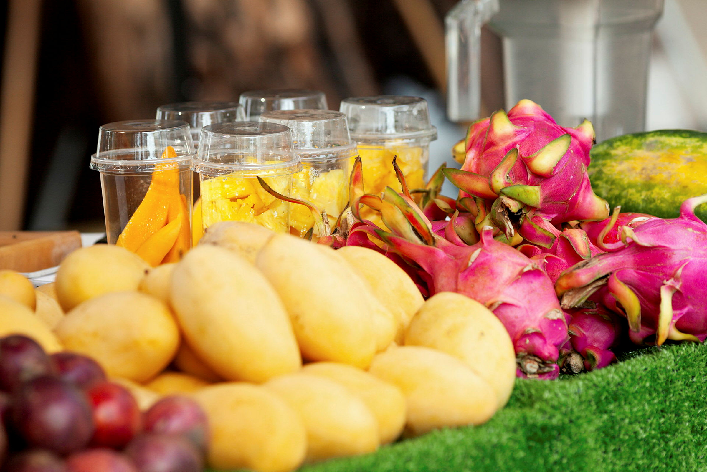Fersk frukt, inkludert mango, dragefrukt og oppskåret frukt i plastbeger. (AI-generert tekst)