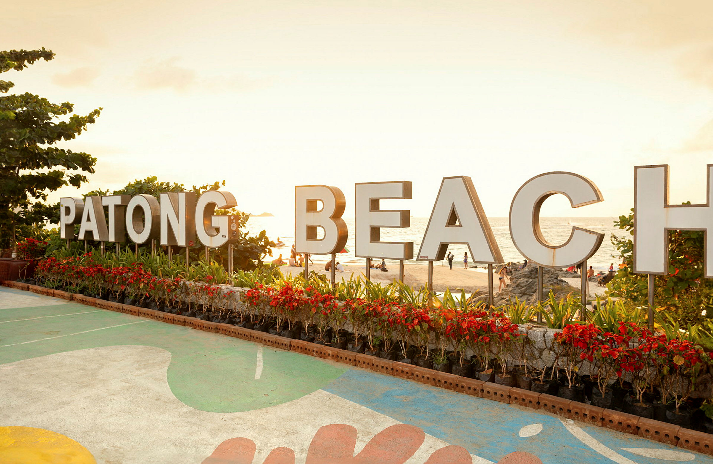 Skilt med teksten 'Patong Beach' foran stranden. (AI-generert tekst)