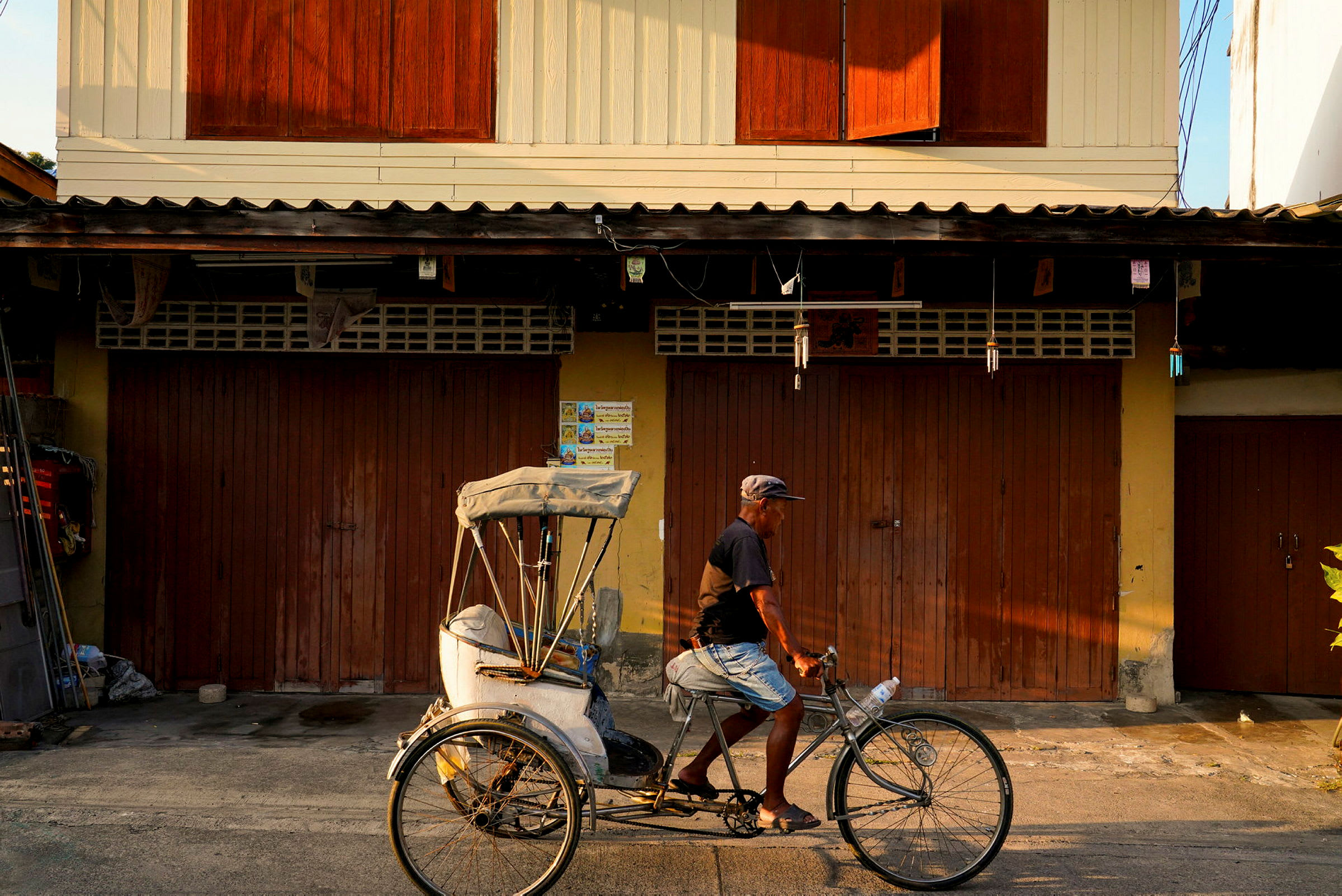 En sykkel-rickshaw foran en bygning med mørke treporter. (AI-generert tekst)