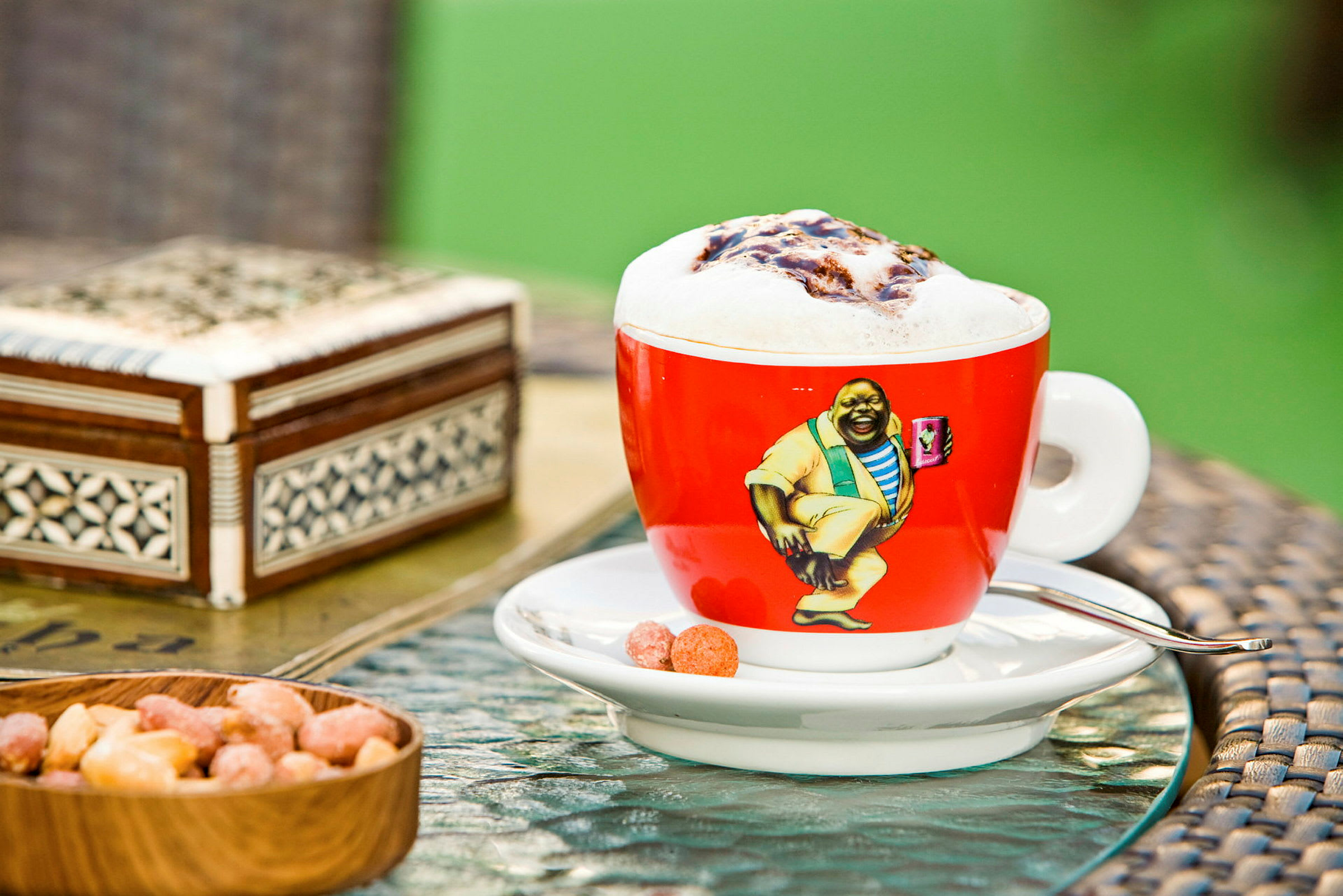 En kopp kaffe med skum melk på et bord sammen med noen snacks. (AI-generert tekst)
