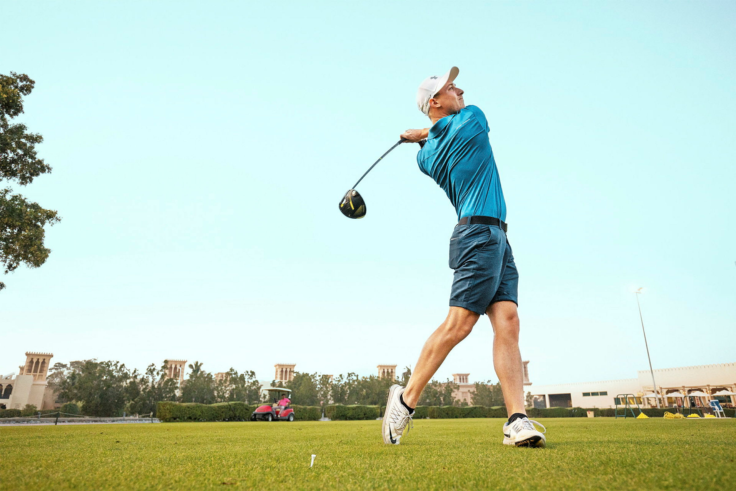 Person spiller golf og svinger en kølle på en grønn golfbane. (AI-generert tekst)