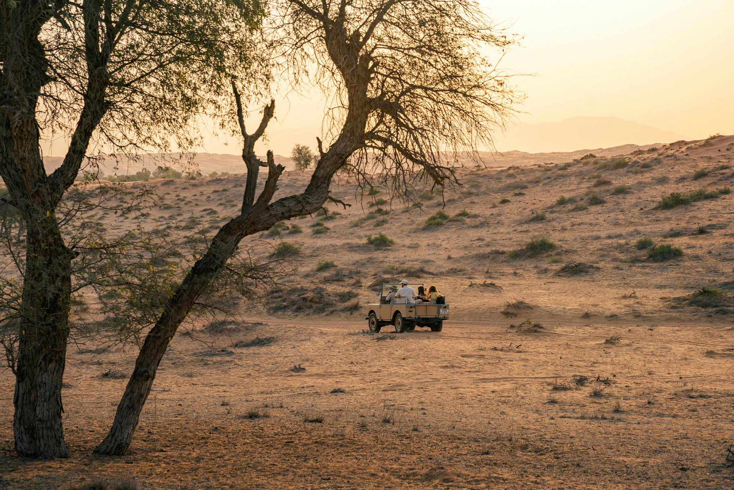En jeep kjører gjennom et ørkenlandskap ved solnedgang. (AI-generert tekst)