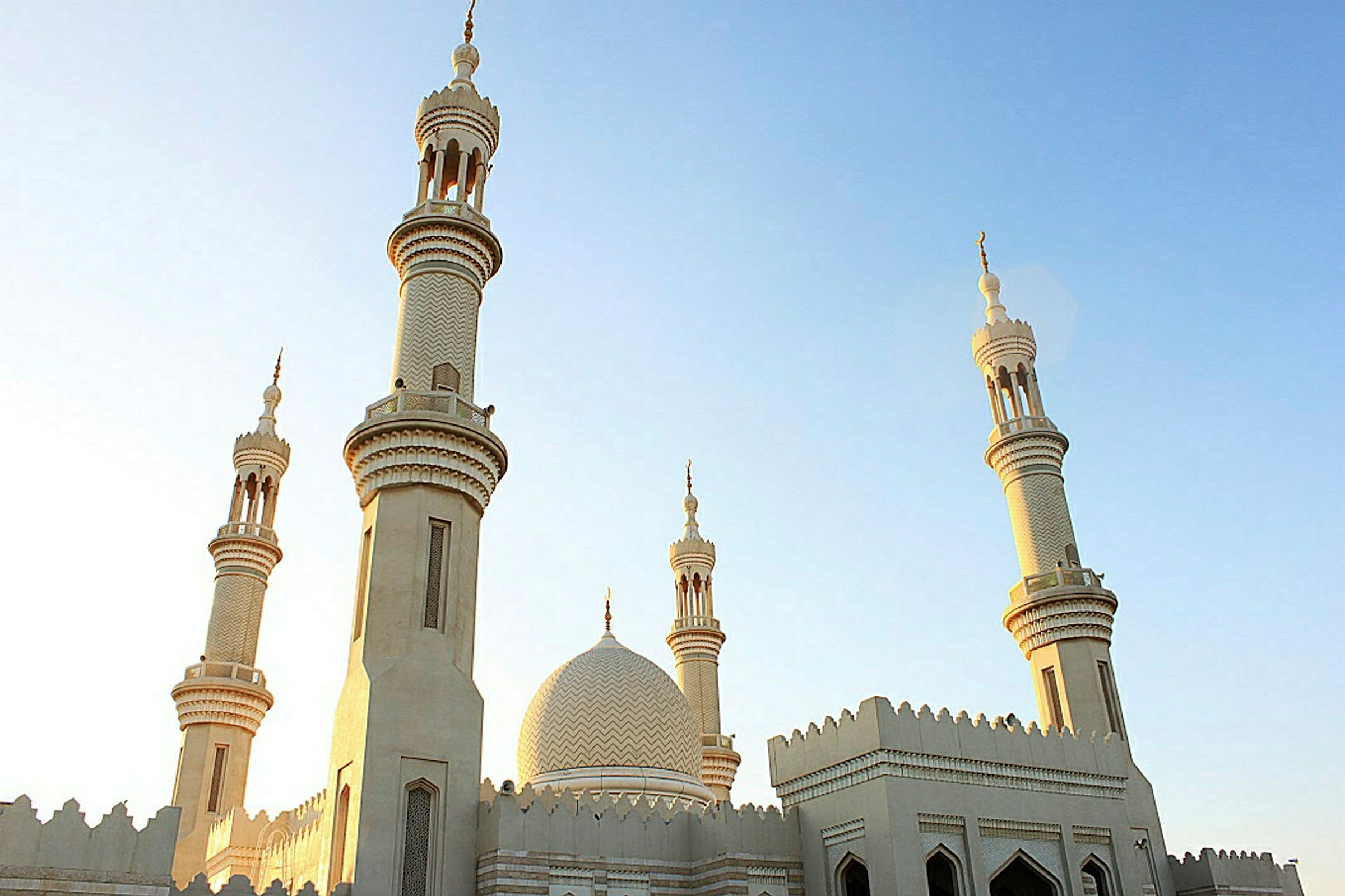 En moské med flere minareter mot en klar himmel. (AI-generert tekst)