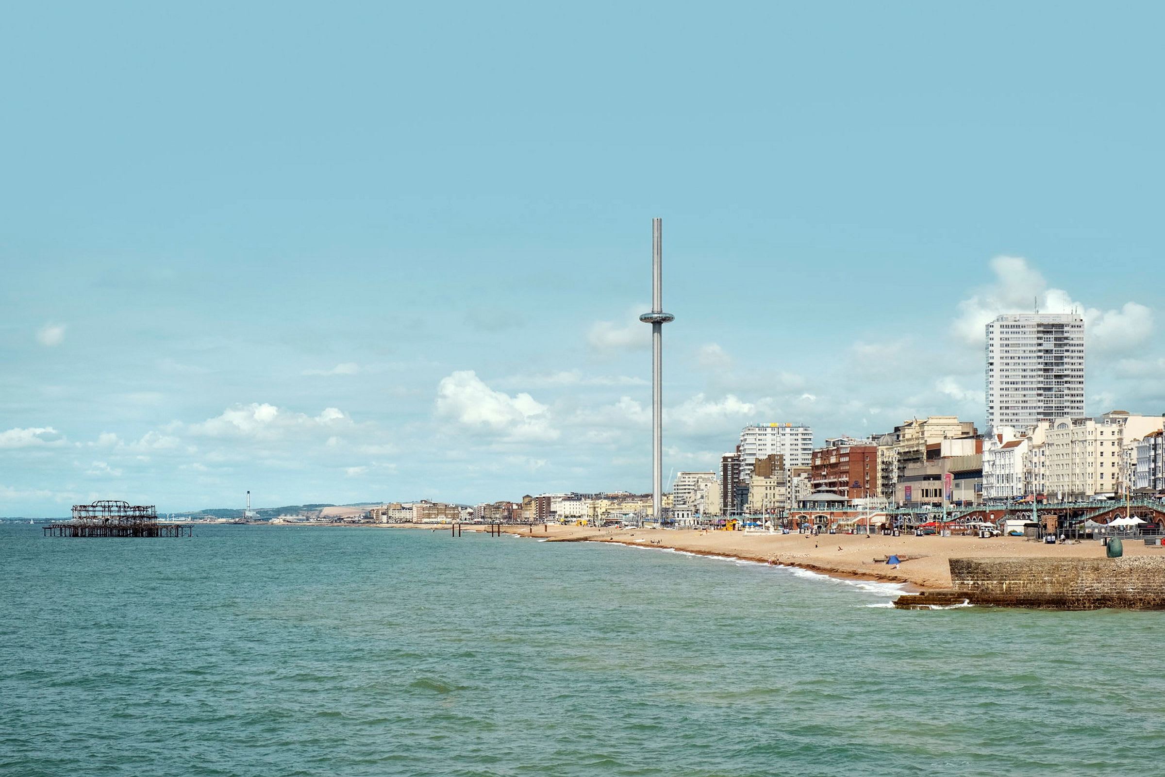 Utsikt over sjøen og stranden i Brighton med i360-tårnet og bygninger i bakgrunnen. (AI-generert tekst)