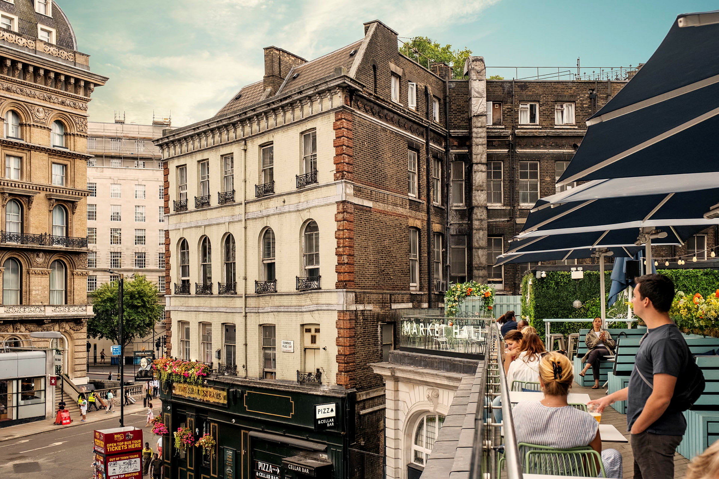 Utsikt over et bymiljø med historiske bygninger og en terrasse med sitteplasser. (AI-generert tekst)