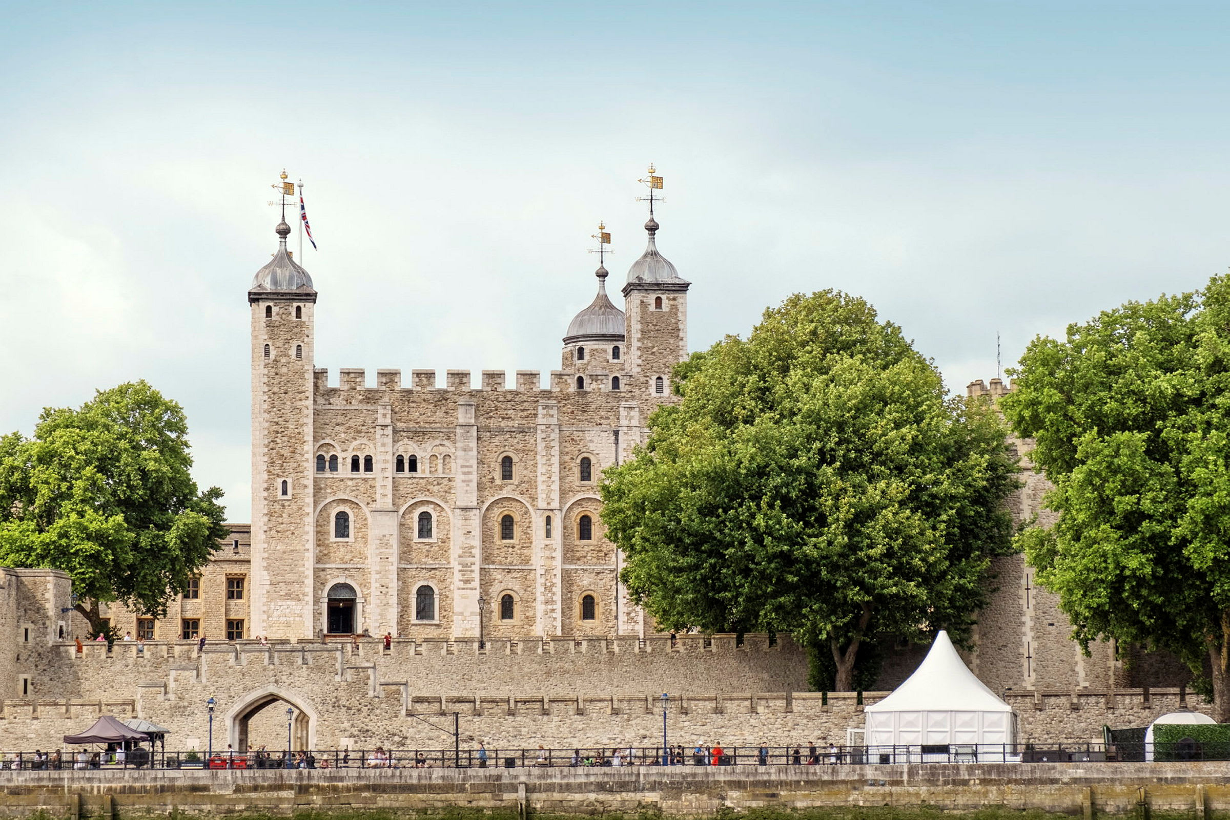 En historisk steinbygning med tårn og grønne trær foran. (AI-generert tekst)