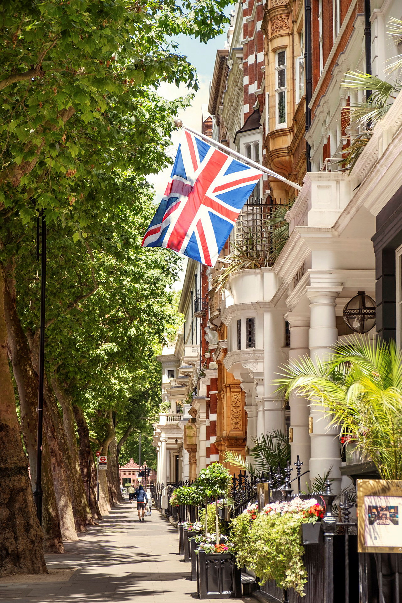 Britisk flagg som henger fra en bygning ved en frodig gate. (AI-generert tekst)