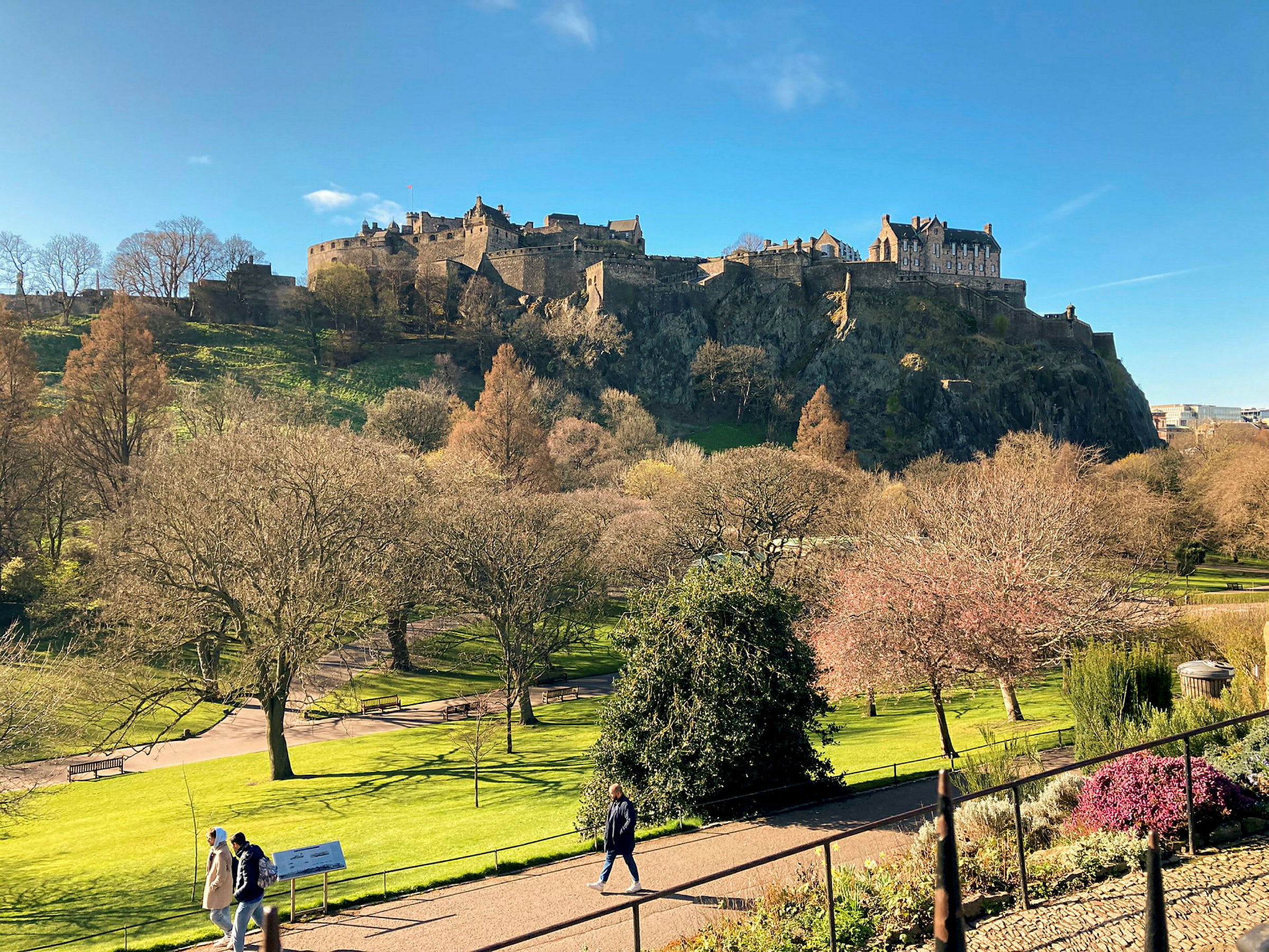 Utsikt over Edinburgh Castle på en solrik dag, omgitt av trær og grøntområder. (AI-generert tekst)