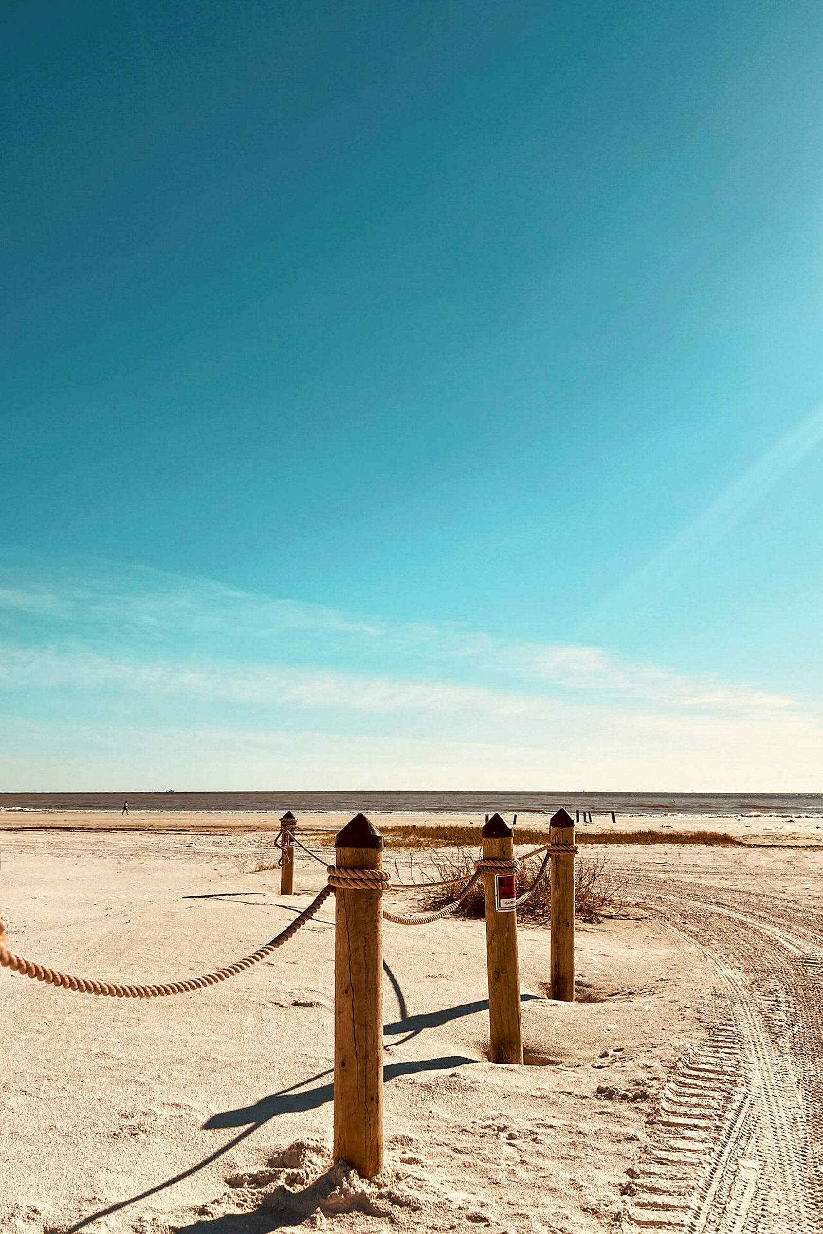 Trestolper med tau ved en strand. (AI-generert tekst)