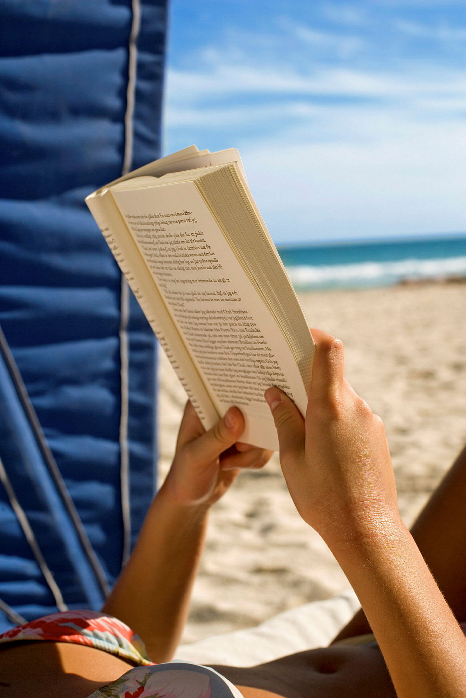 En person leser en bok på en strand. (AI-generert tekst)
