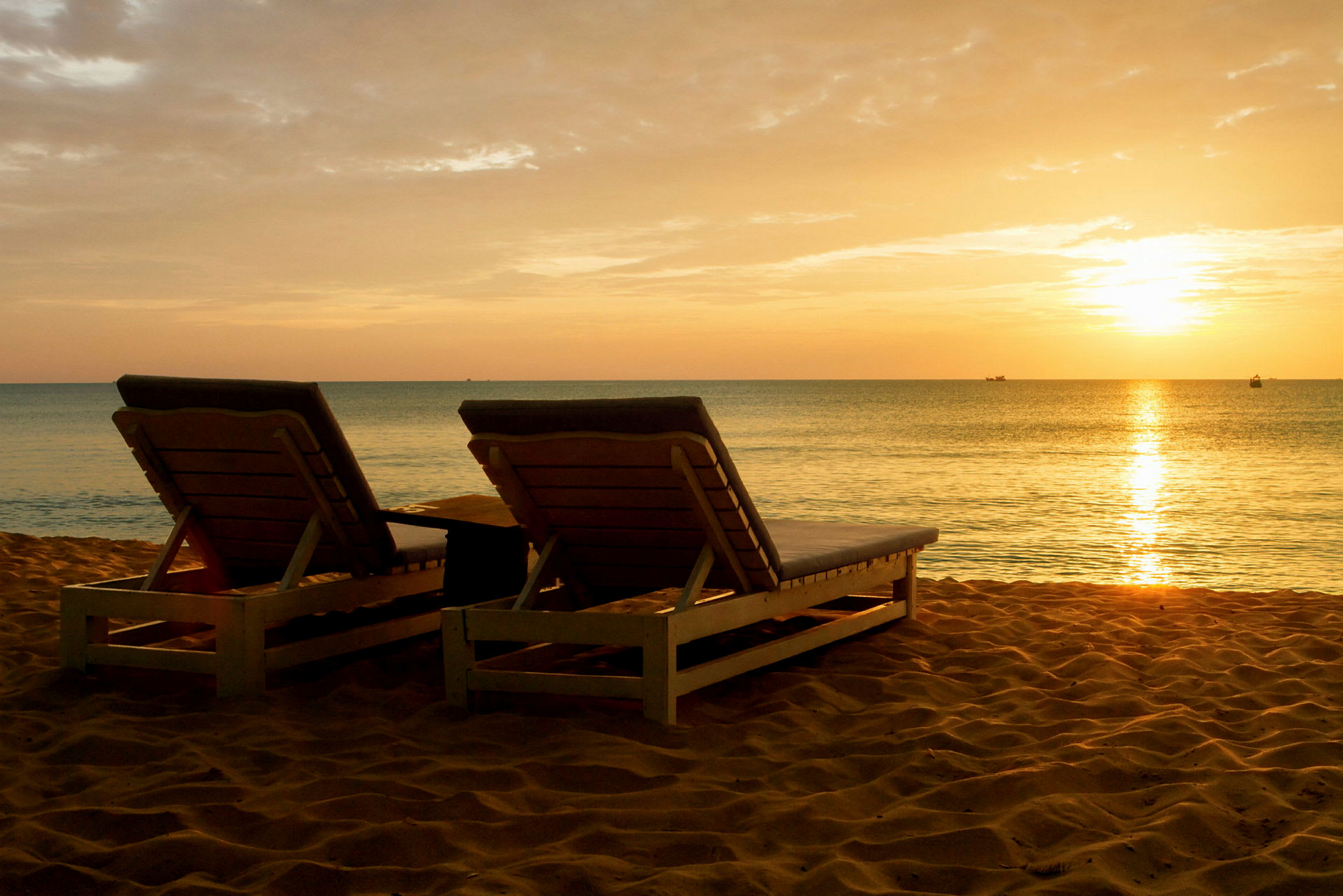 To solsenger på en sandstrand ved solnedgang. (AI-generert tekst)
