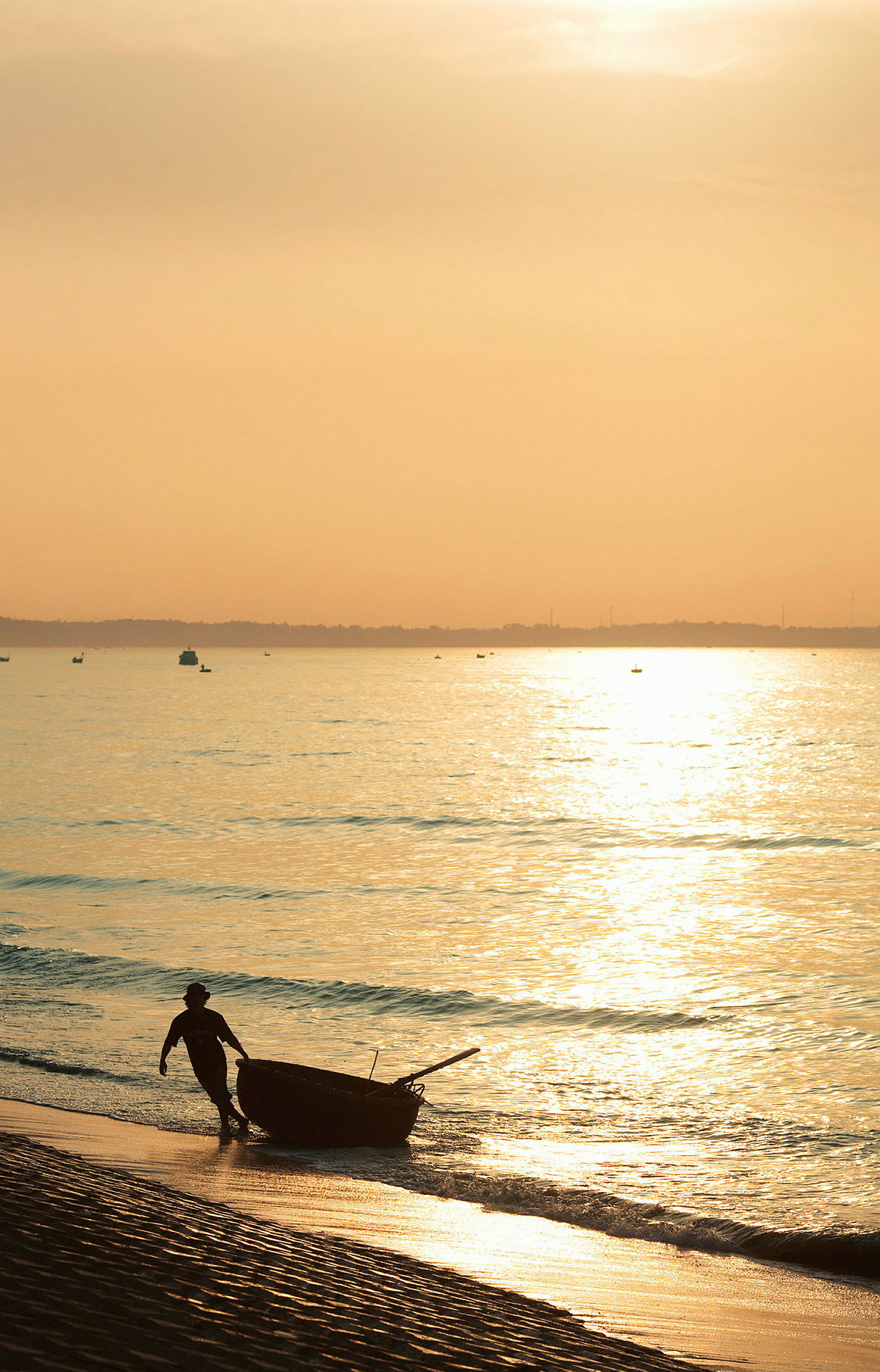 En person drar en båt fra stranden ved soloppgang eller solnedgang. (AI-generert tekst)