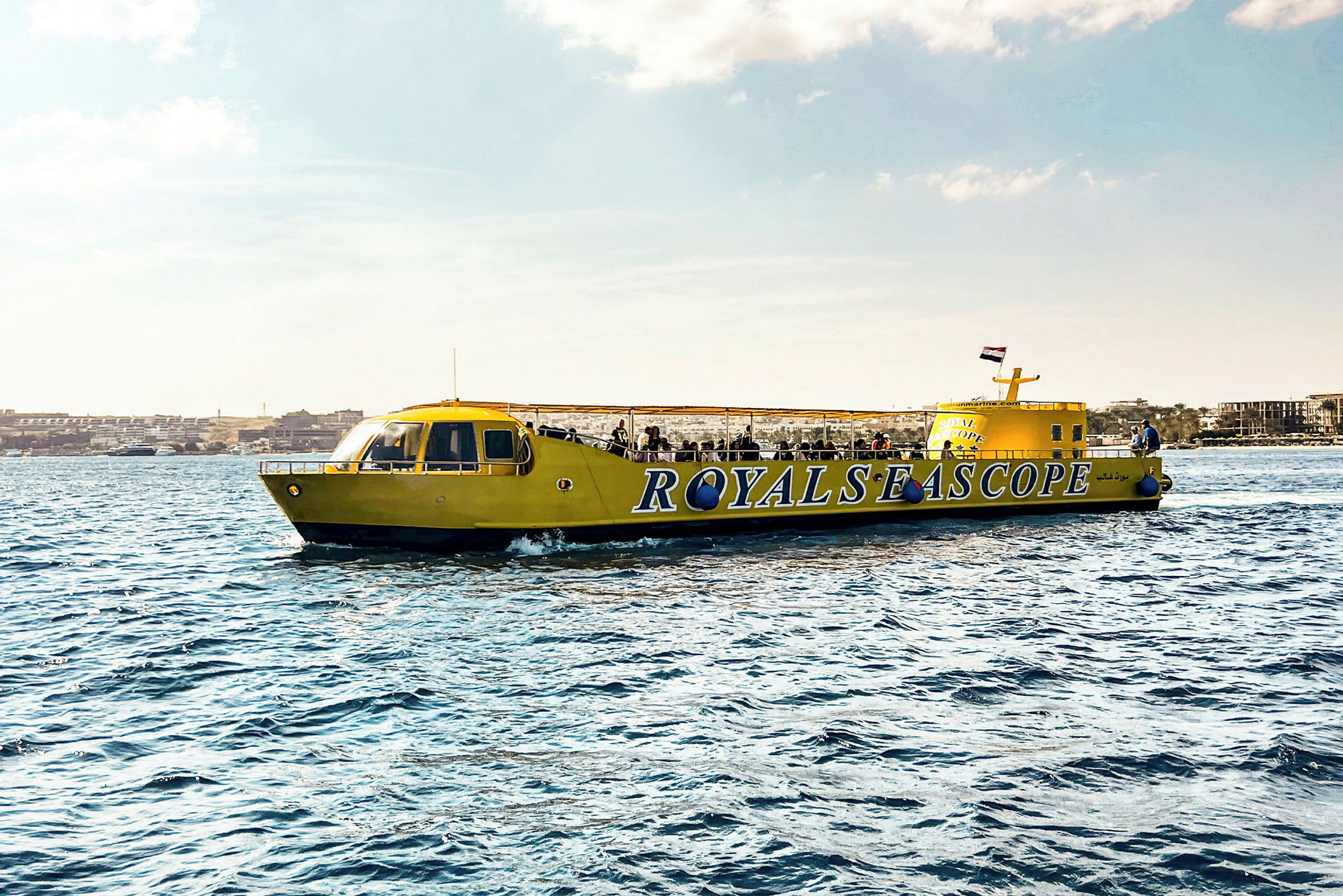 En gul sightseeingbåt med teksten 'ROYALS SEA SCOPE' vises på vannet. (AI-generert tekst)