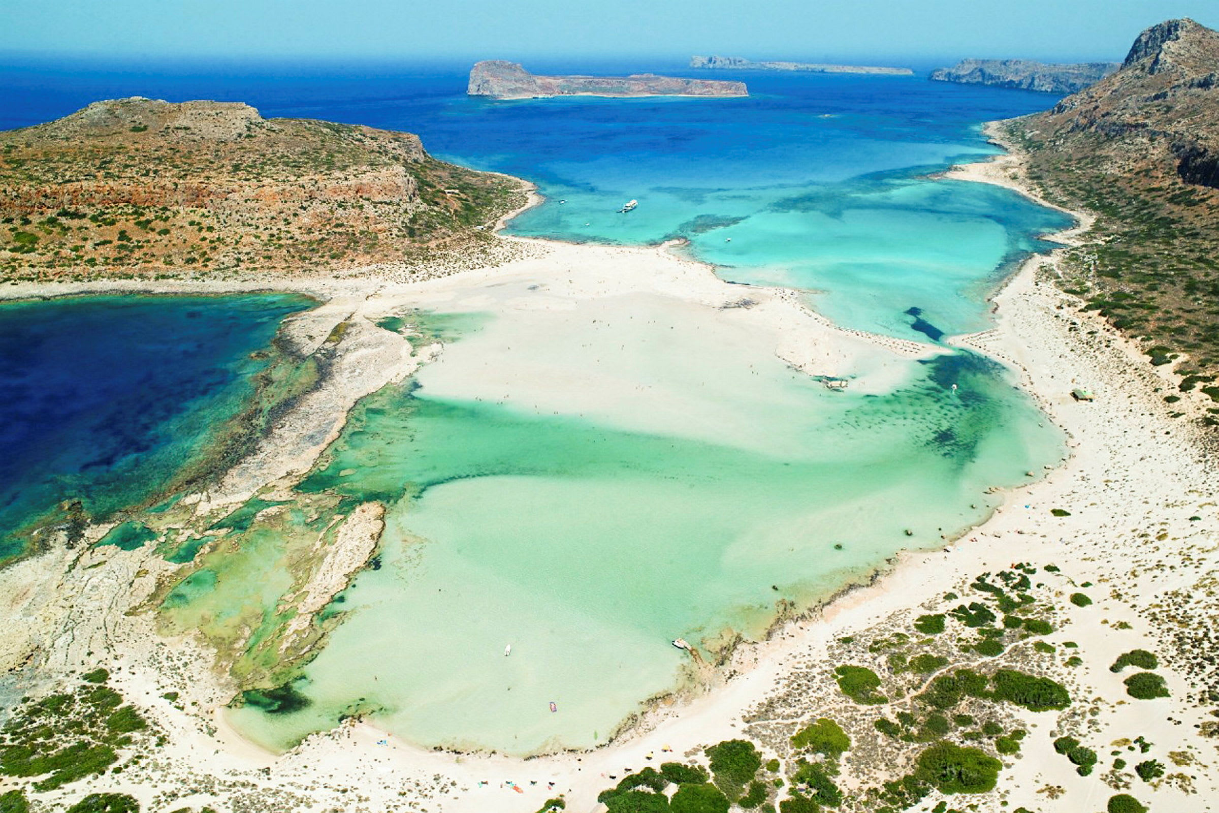 Flyfoto av en strand med turkis vann og omkringliggende sanddyner. (AI-generert tekst)