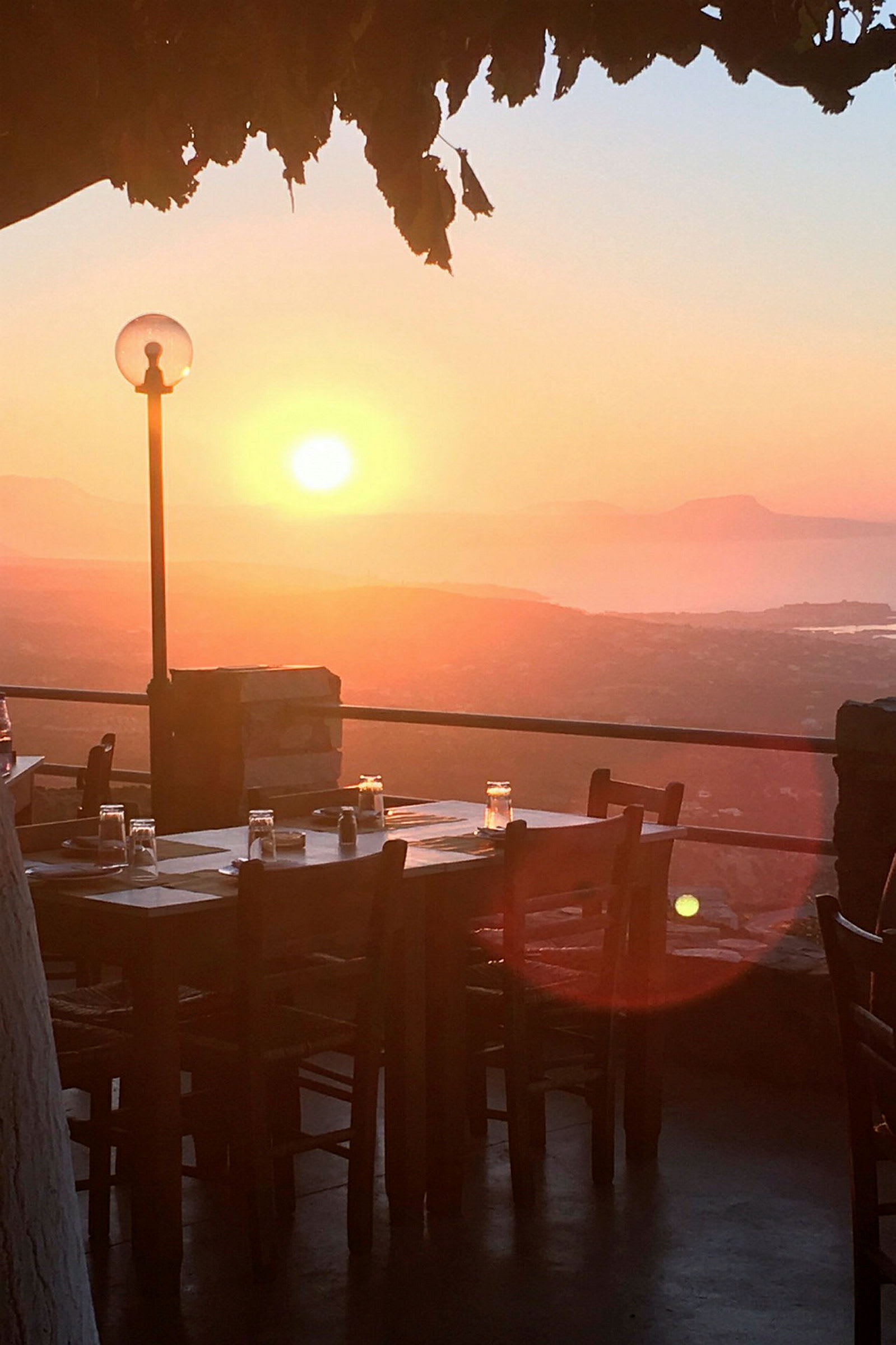 Et dekket bord for middag utendørs ved solnedgang, med utsikt over landskapet. (AI-generert tekst)