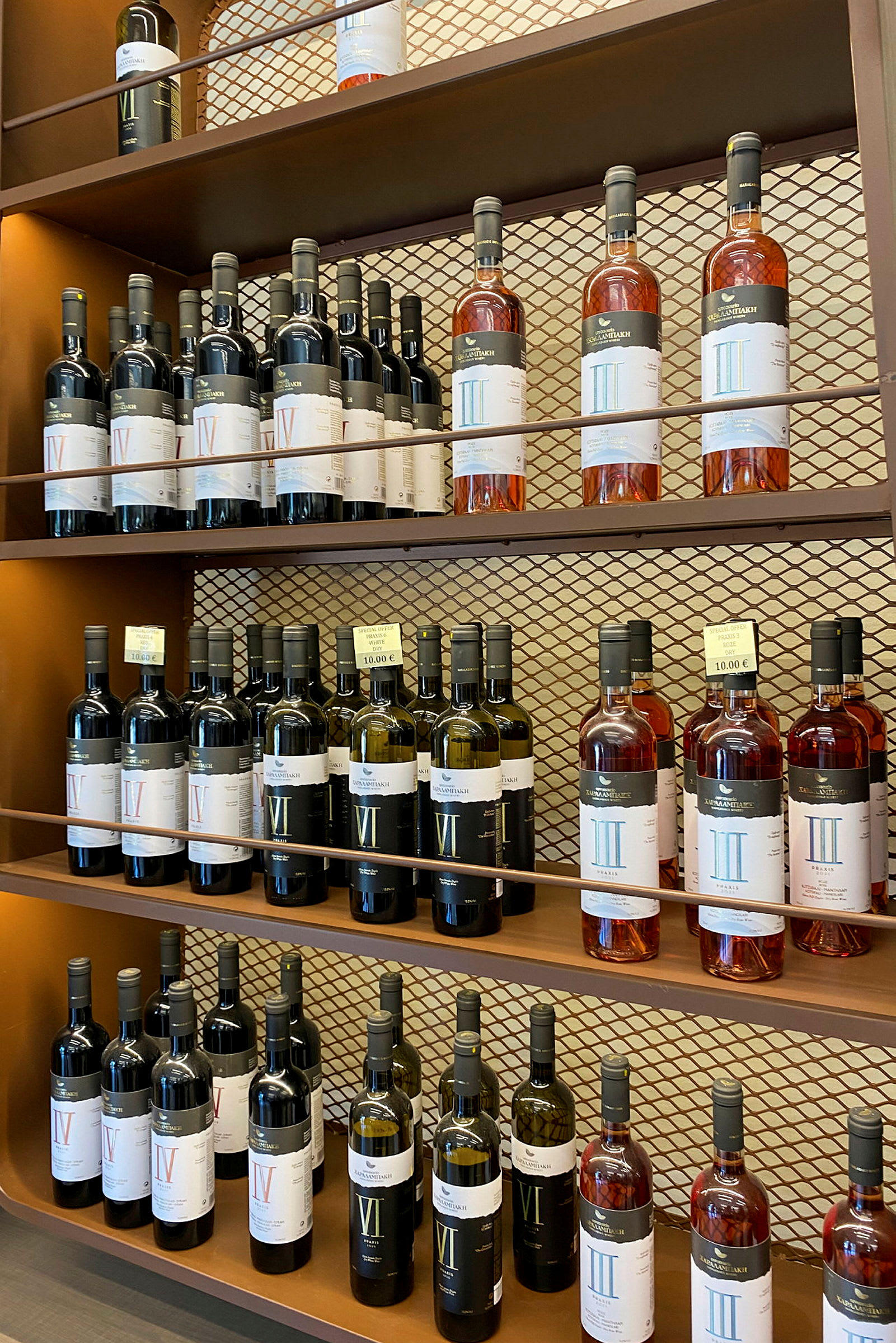 Hylle med flasker med vin i ulike typer og etiketter, på en bronsefarget bakgrunn. (AI-generert tekst)