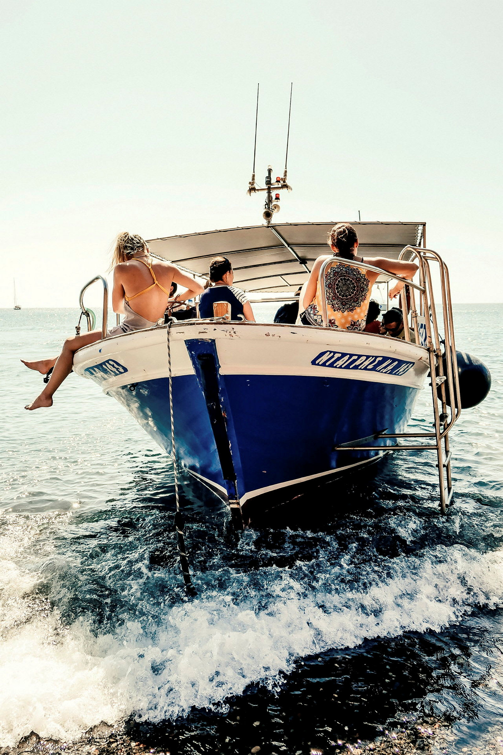En motorbåt med mennesker som sitter på dens foran del i havet. (AI-generert tekst)