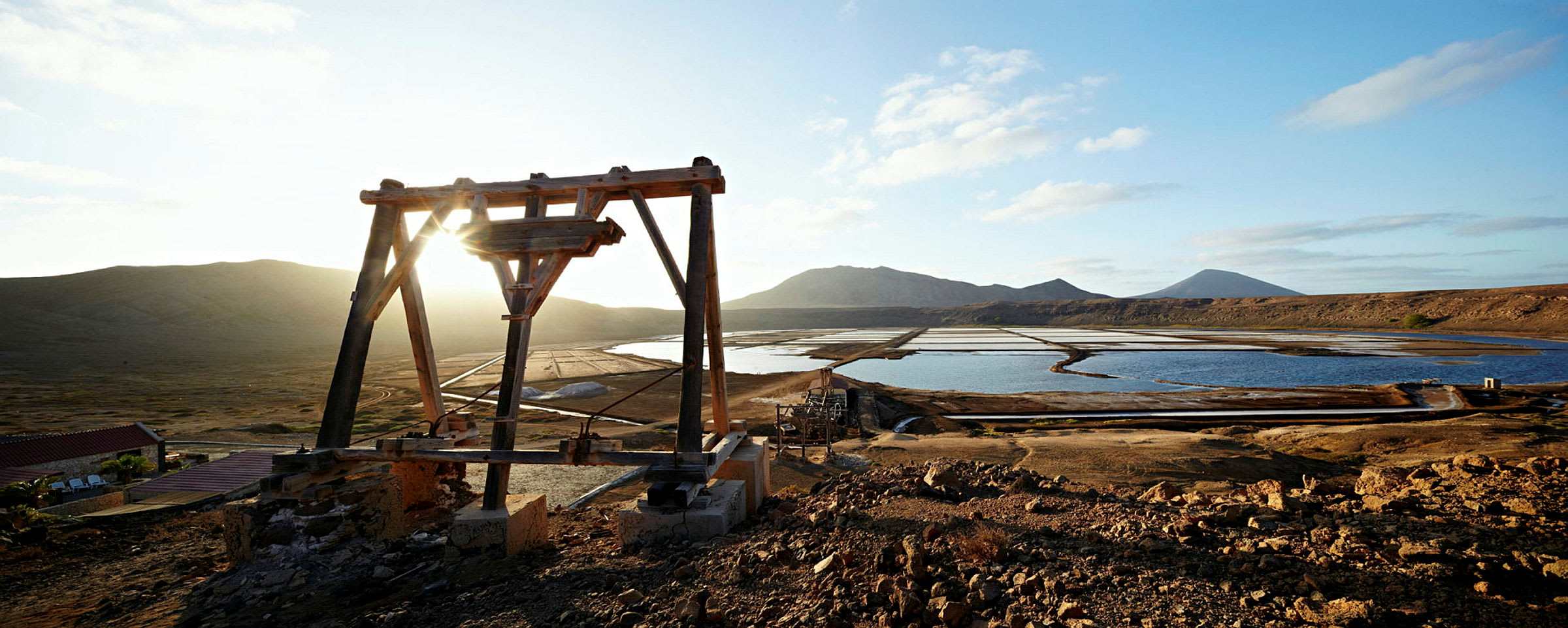 En trestruktur ved saltbassenger med fjell i bakgrunnen. (AI-generert tekst)