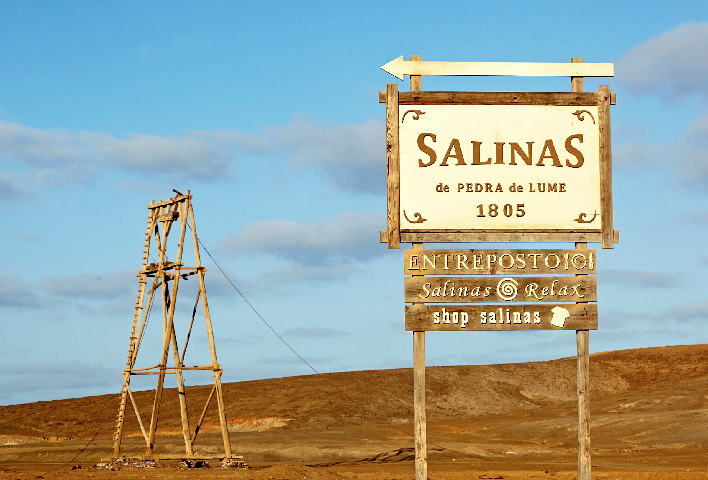 Skilt som markerer Salinas de Pedra de Lume beliggende i et ørkenområde. (AI-generert tekst)