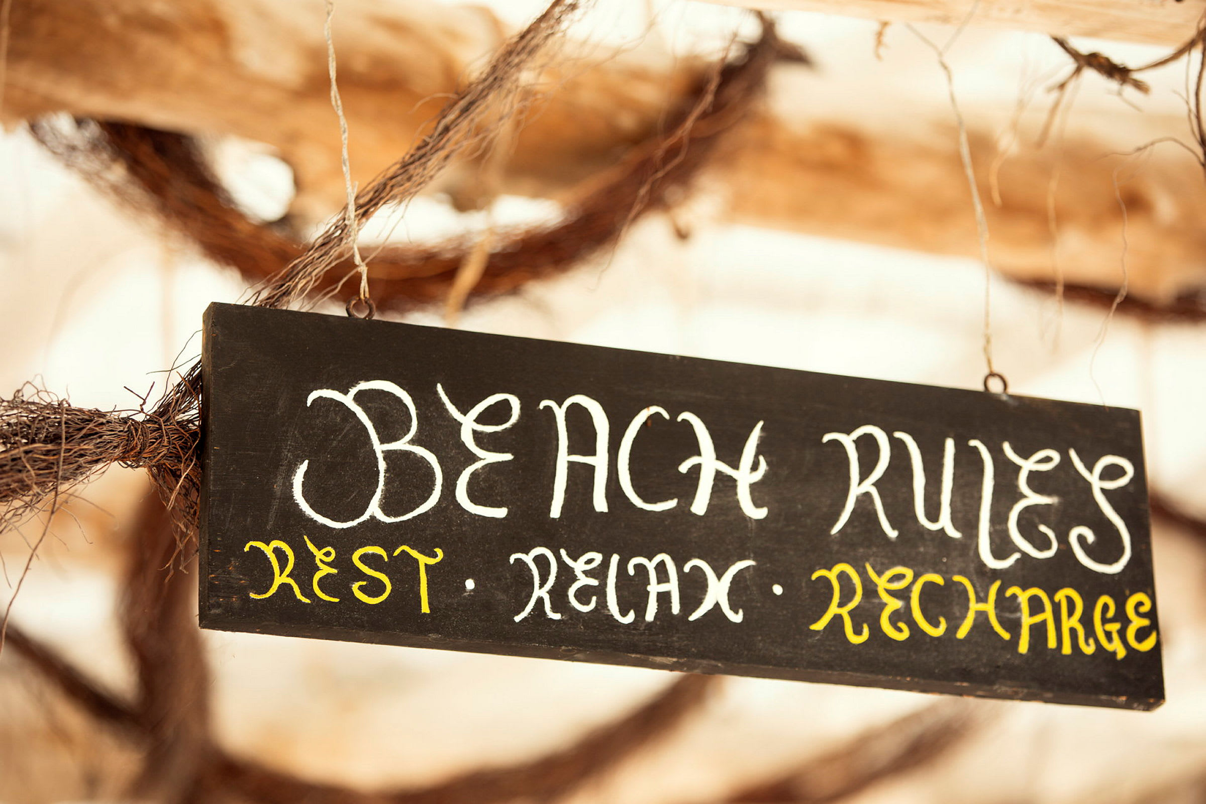 Svart skilt med teksten 'Beach Rules: Rest, Relax, Recharge'. (AI-generert tekst)