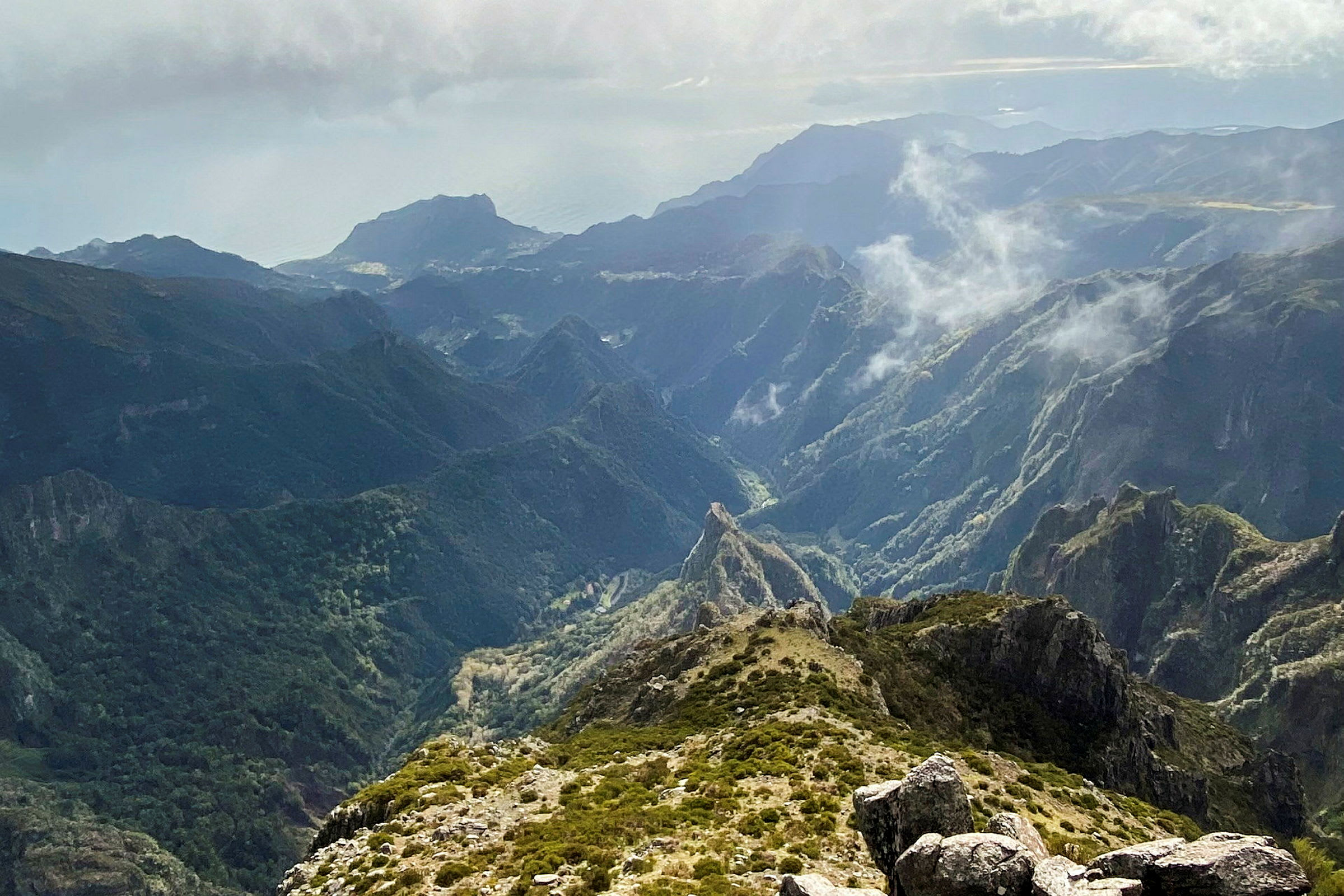 En fjellformasjon med grønne skråninger og tåke i et naturskjønt landskap. (AI-generert tekst)
